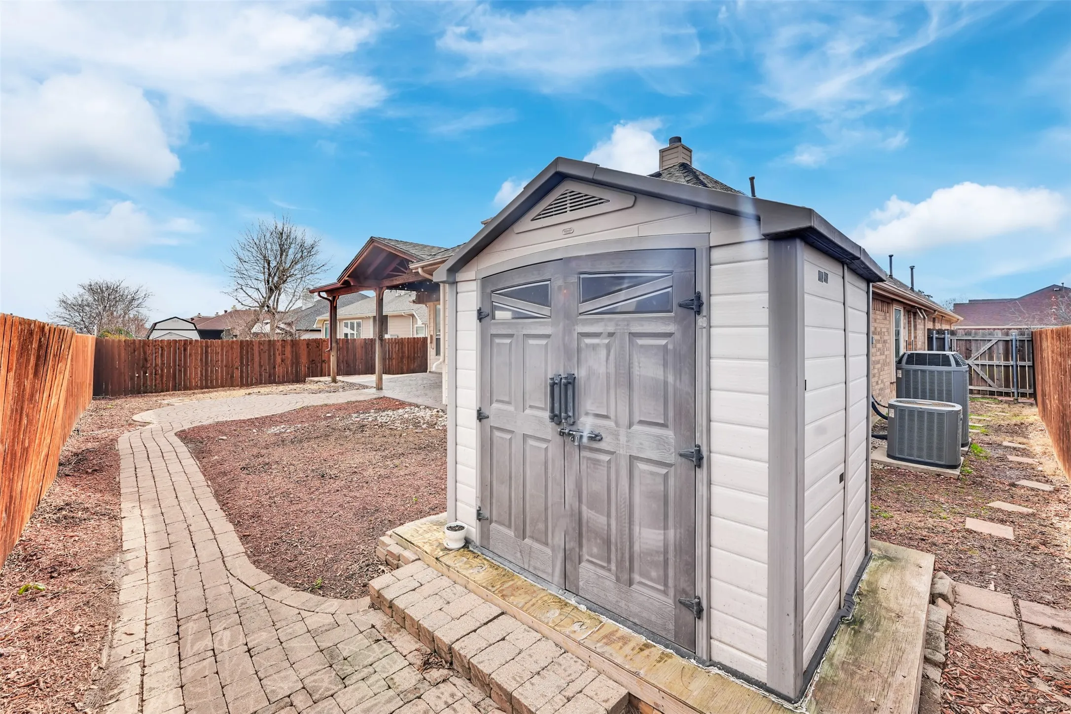 Backyard featuring a paved pathway, privacy fencing, outdoor shed, and covered patio structure