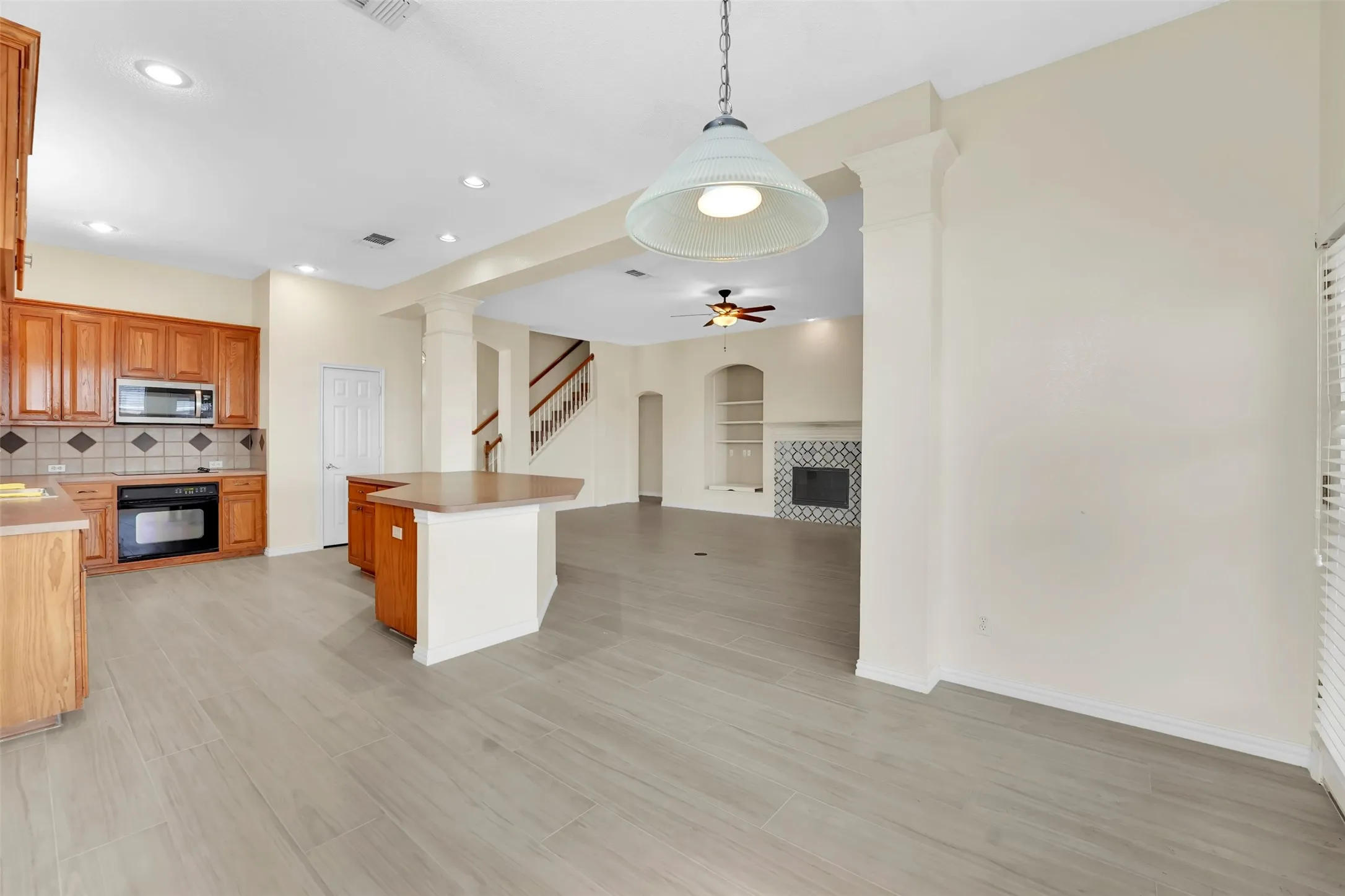 Kitchen featuring wood cabinetry, built-in appliances, a tile backsplash, and an island with a countertop