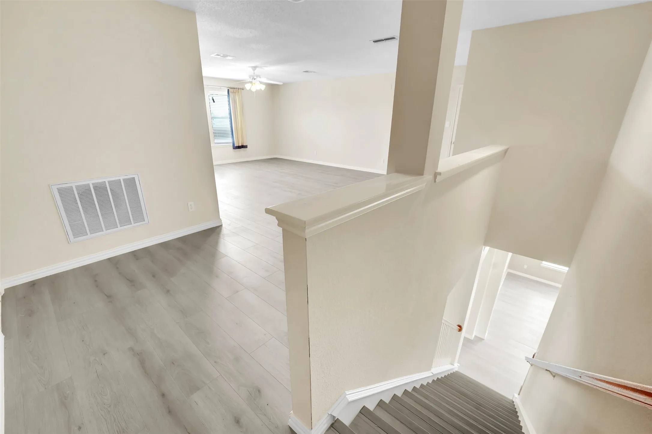 Open-concept living space featuring wood-finish flooring, neutral wall finishes, and abundant natural lighting