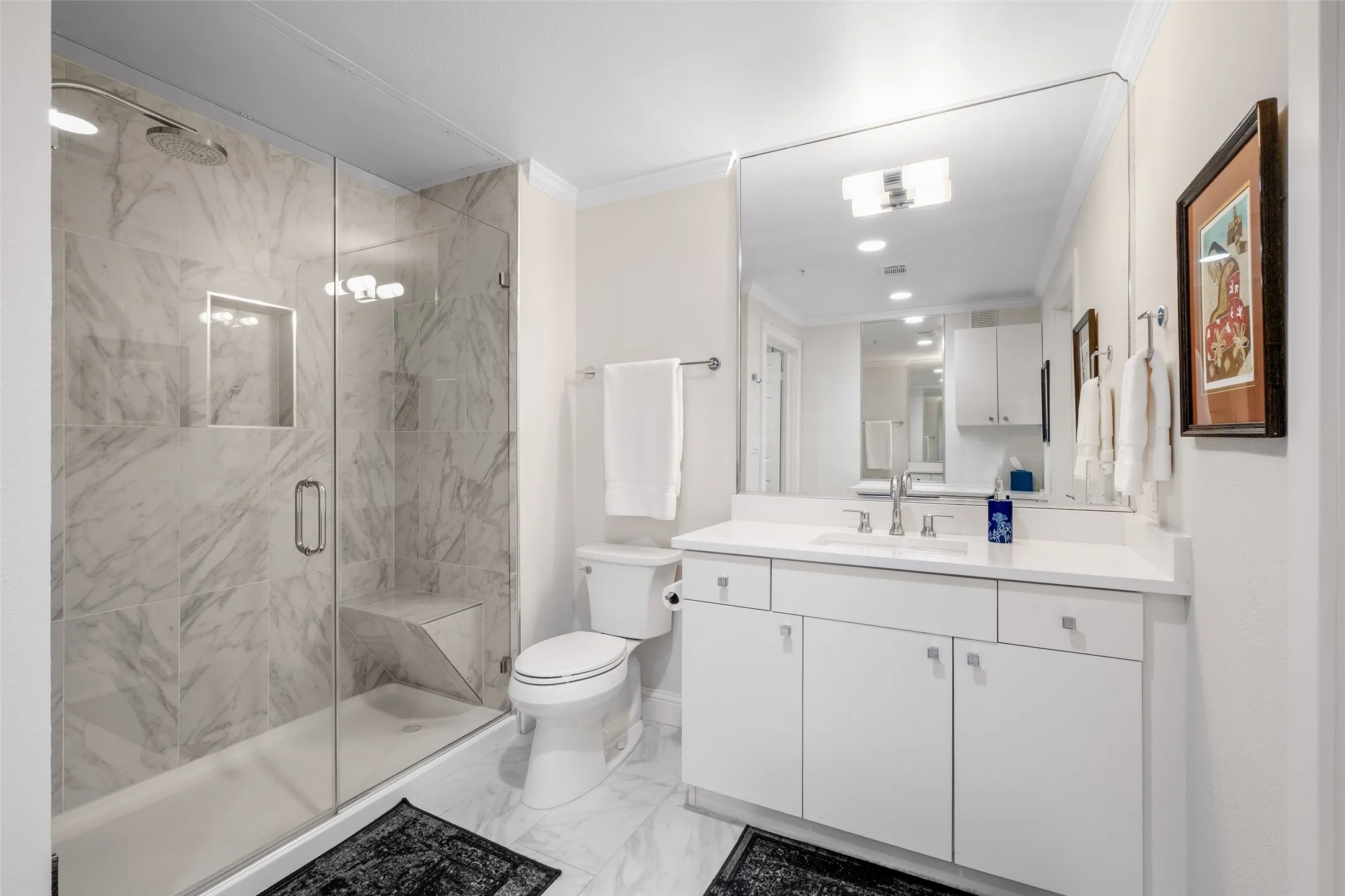 Walk-in shower with clear glass enclosure and integrated bench
