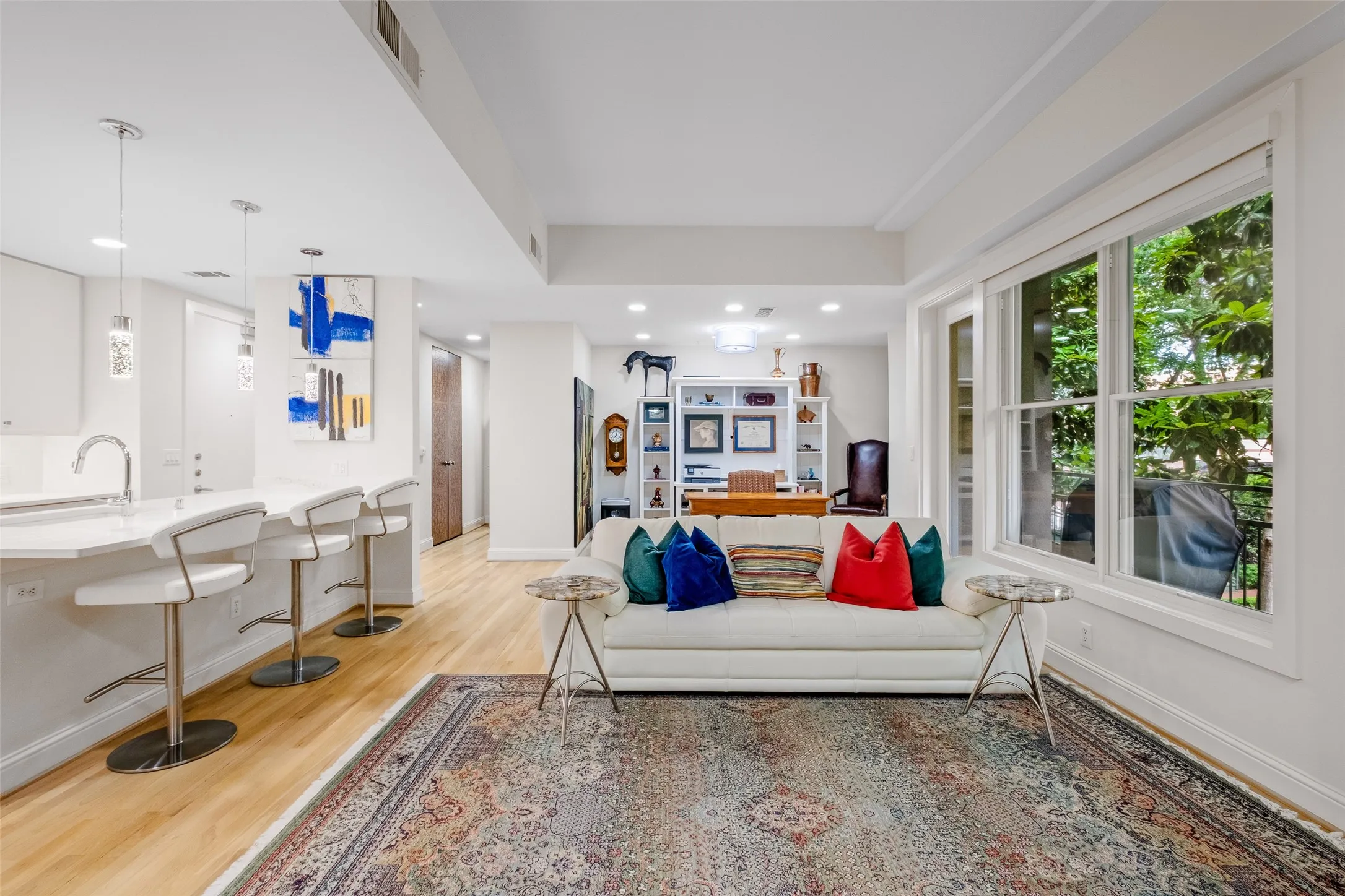 Open-concept living space featuring wood-finish flooring, recessed lighting, and large window panels