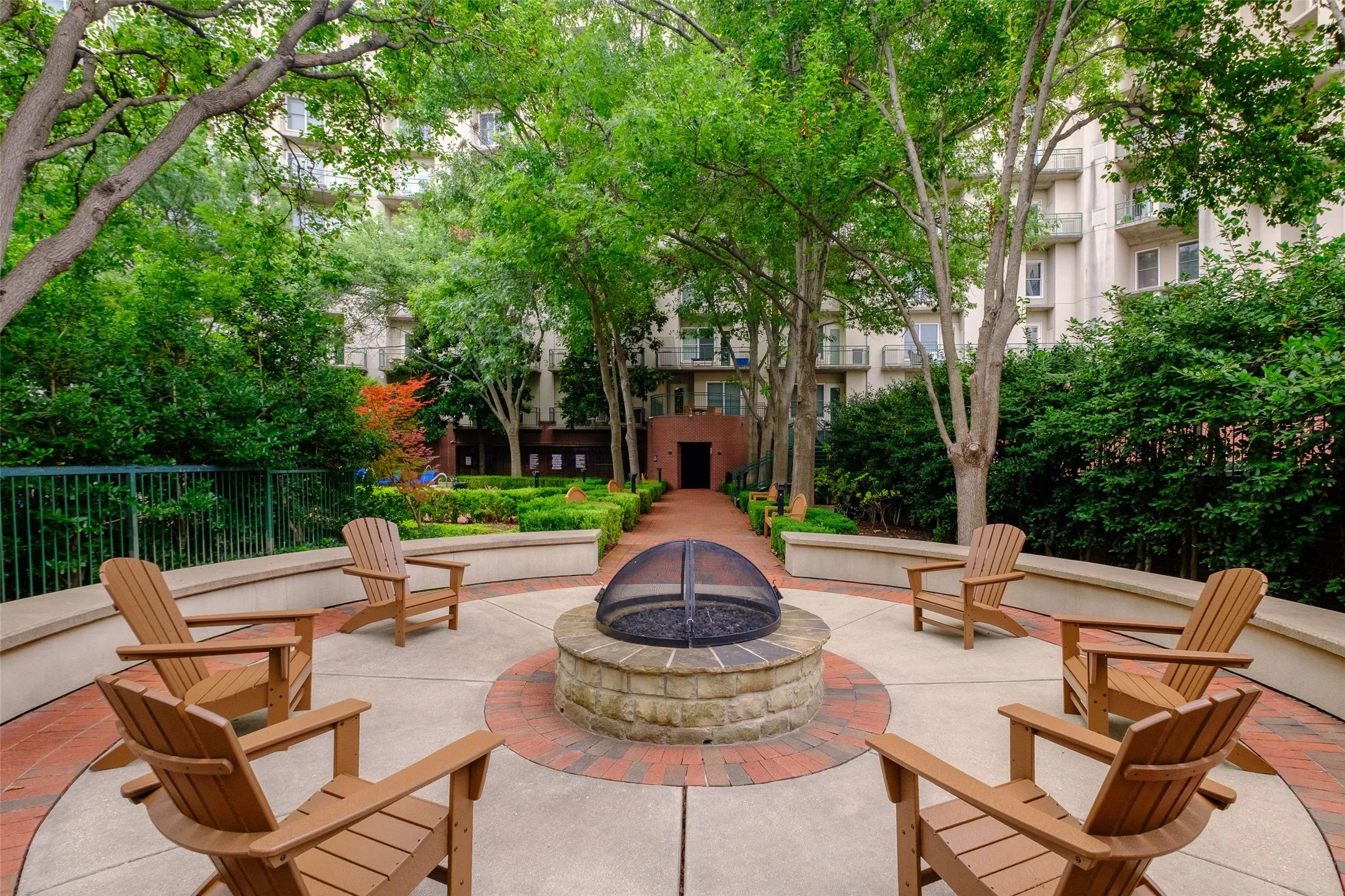 Outdoor patio featuring a stone fire pit with a metal spark screen, surrounded by a circular concrete and brick-finish paver patio
