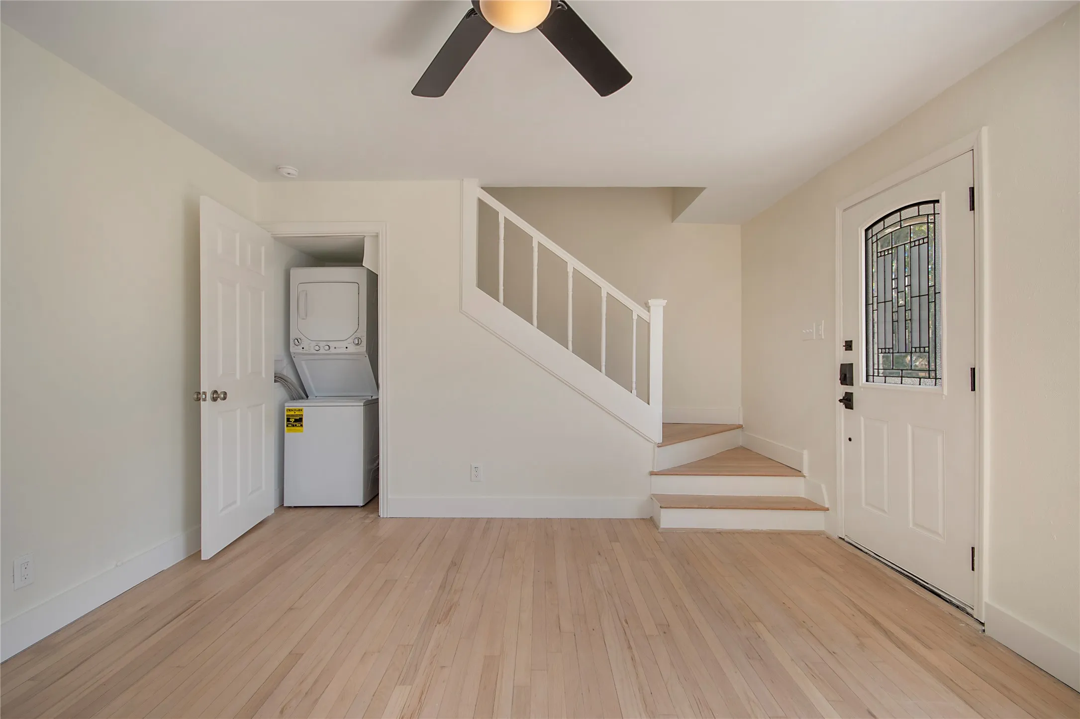 Wood-finish flooring throughout, white painted walls, and a staircase with white balusters