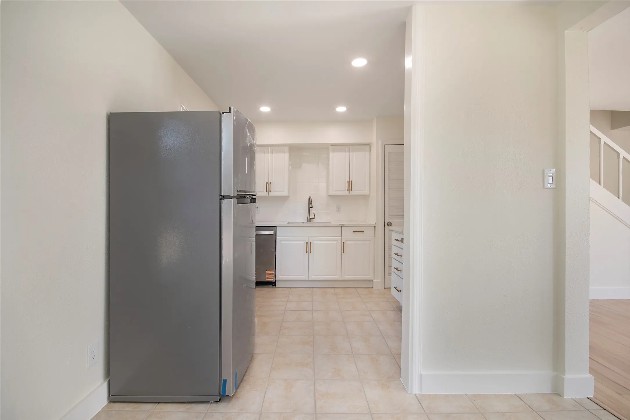 Kitchen featuring white cabinetry with gold-tone hardware, a stainless steel dishwasher, and a dual-basin sink