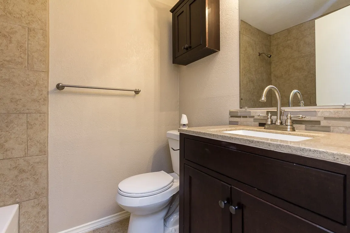 Spa-inspired bathroom featuring a dual-sink vanity with a polished stone countertop, dark cabinetry with ample storage, and a chrome two-handle faucet