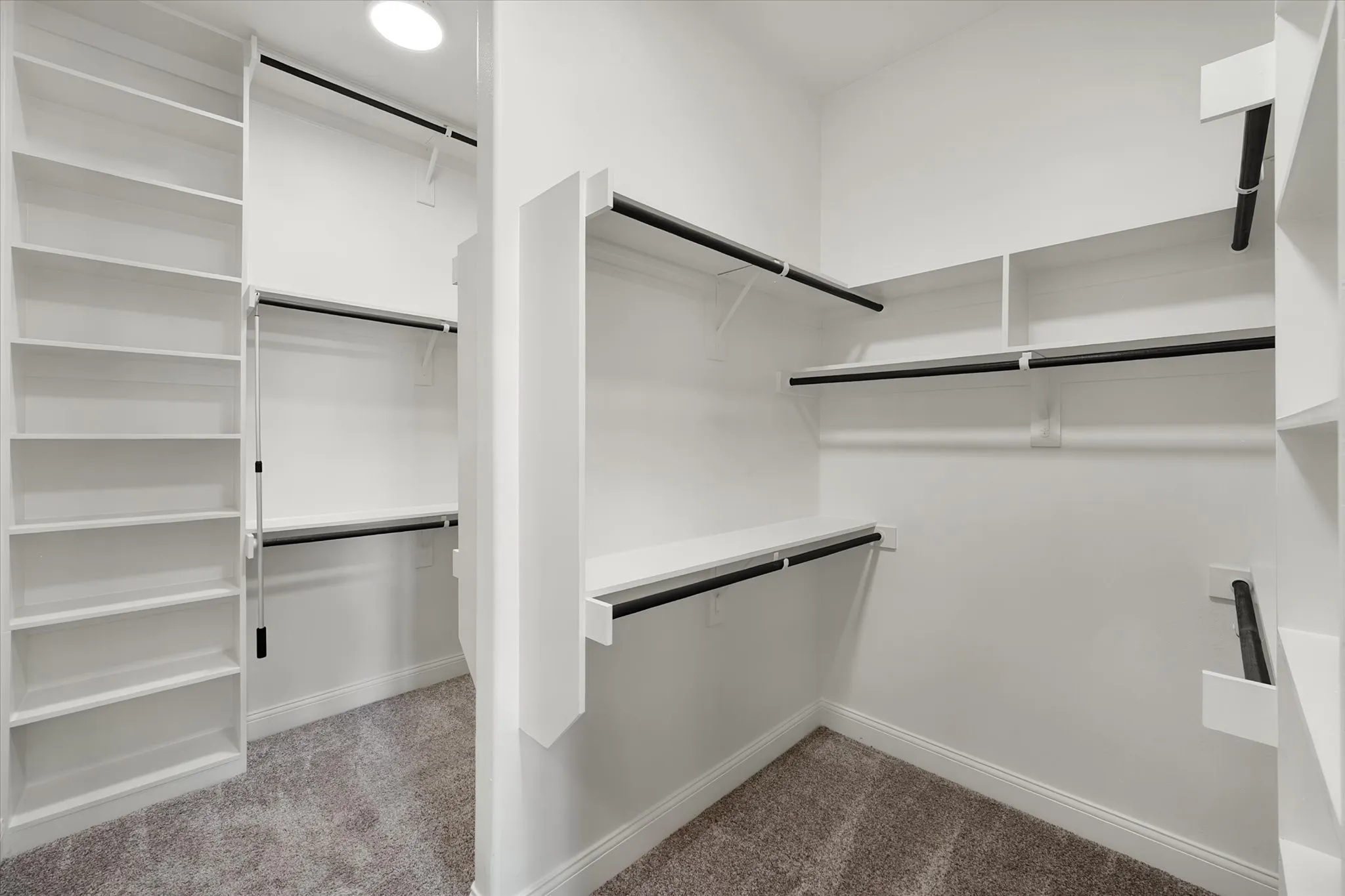 Walk-in closet featuring built-in shelving, multiple hanging rods, and recessed lighting