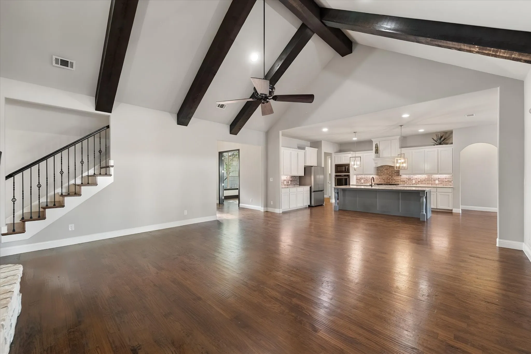 Open-concept living space featuring exposed ceiling beams, a ceiling fan, and recessed lighting throughout