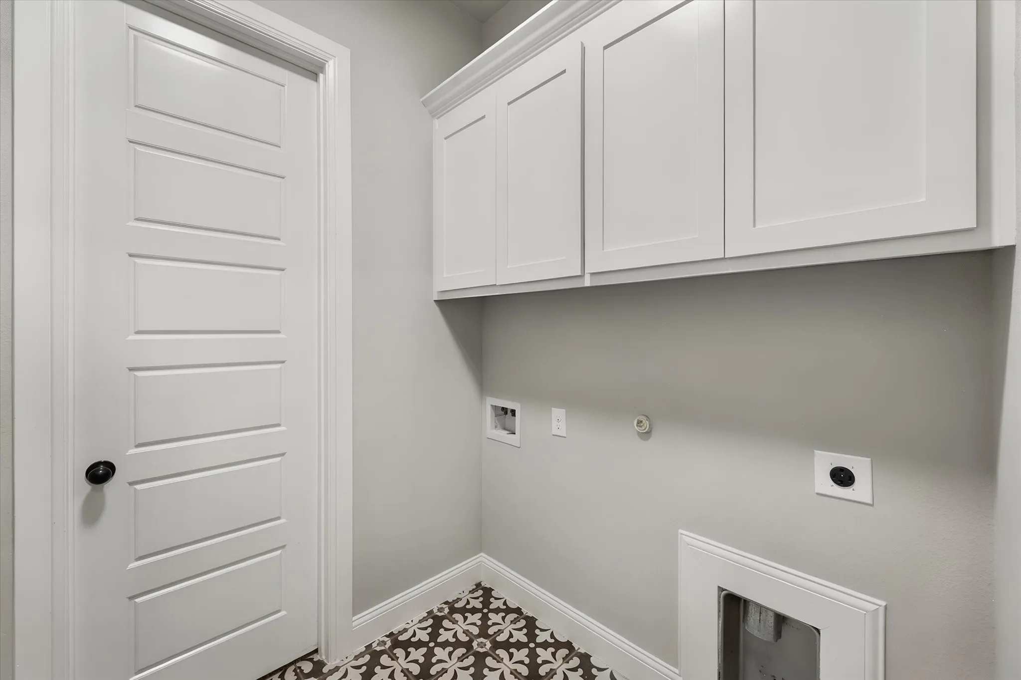 Dedicated laundry room featuring white cabinetry with ample storage, neutral walls, polished concrete flooring, and strategically placed electrical outlets for appliance connections