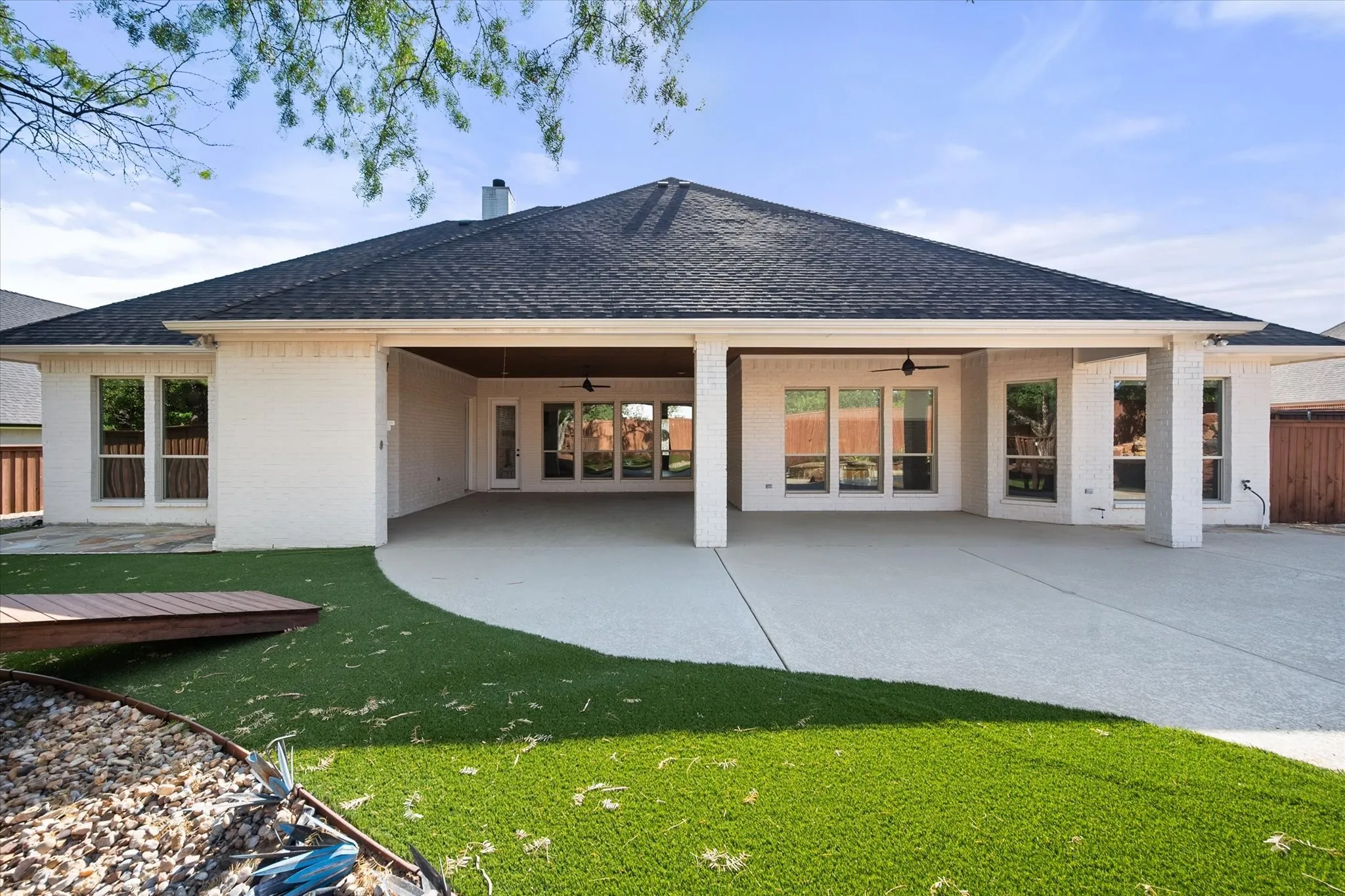 Modern single-story residence featuring a covered alfresco entertaining area with multiple glass sliding doors, white columns, and polished concrete flooring
