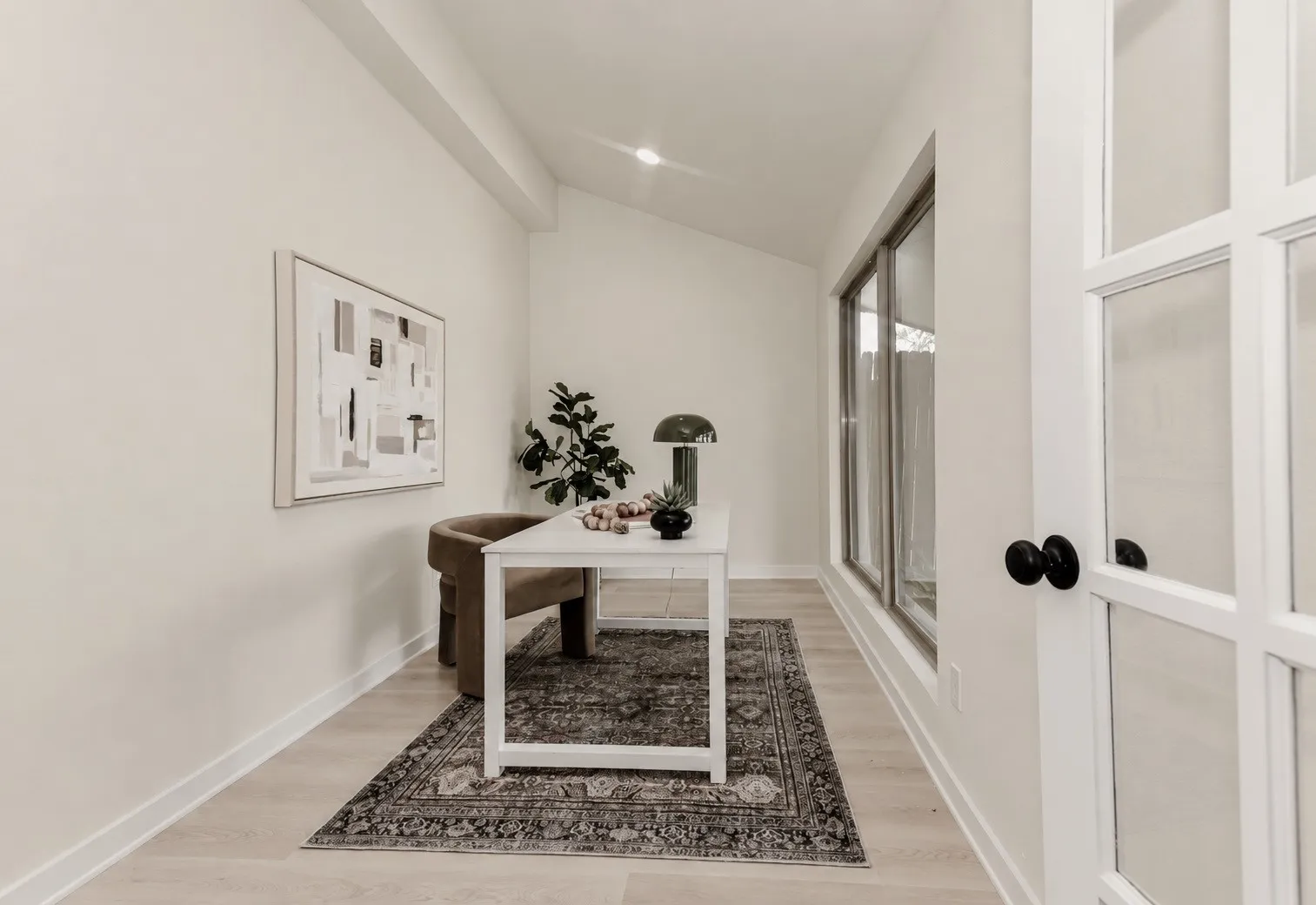 The office area has an expansive window array, wood-finish flooring, and a glass-paned door with black hardware