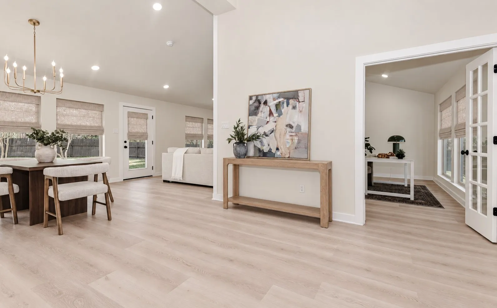 Light wood-finish flooring throughout, vaulted ceilings, recessed lighting, and French doors create an open feeling