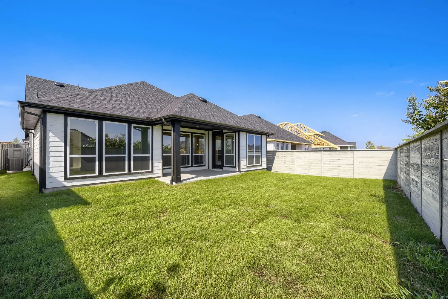 Expansive backyard featuring a manicured lawn, concrete patio, and privacy fencing