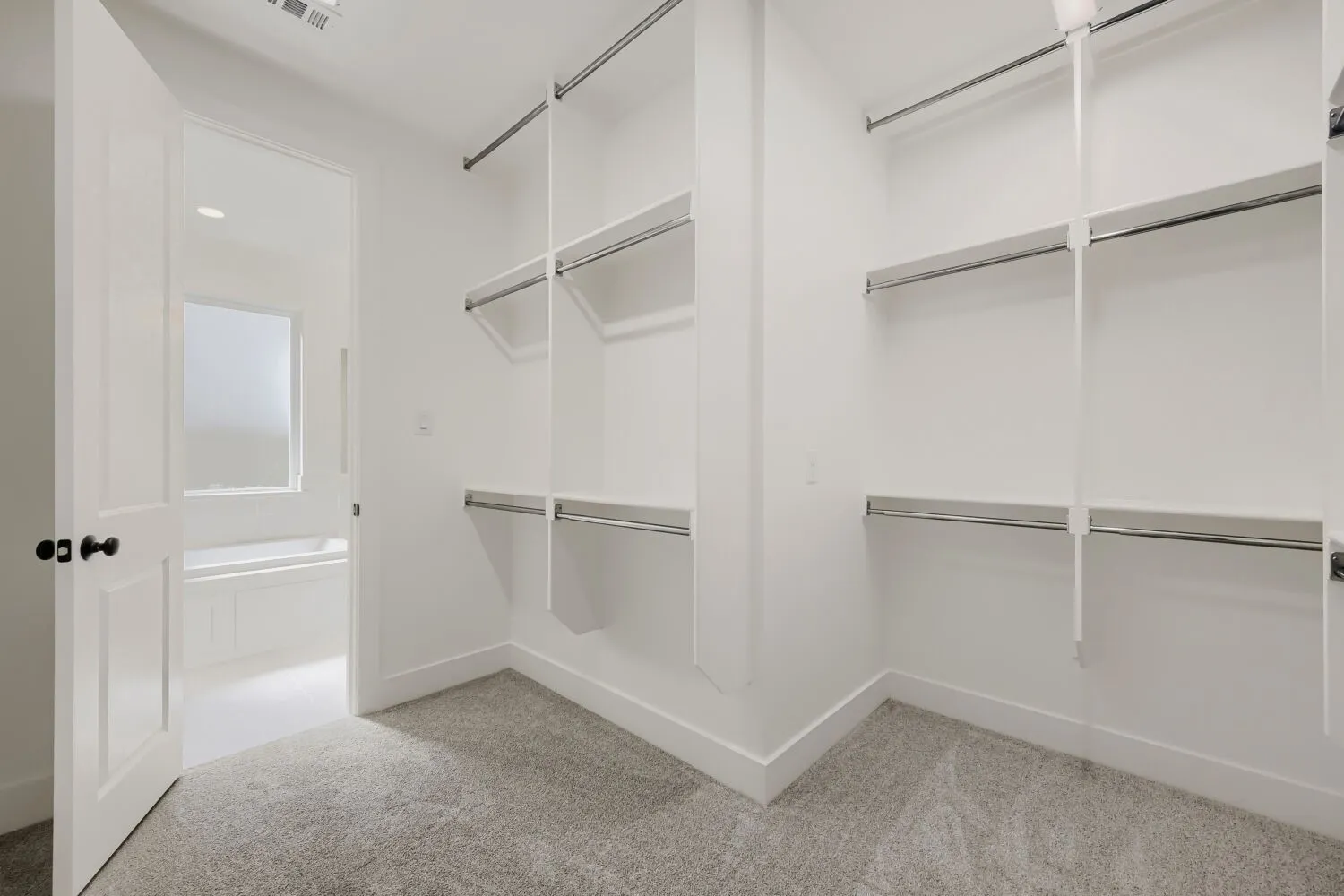 Walk-in closet with carpet flooring, white walls, built-in shelving, and hanging rods