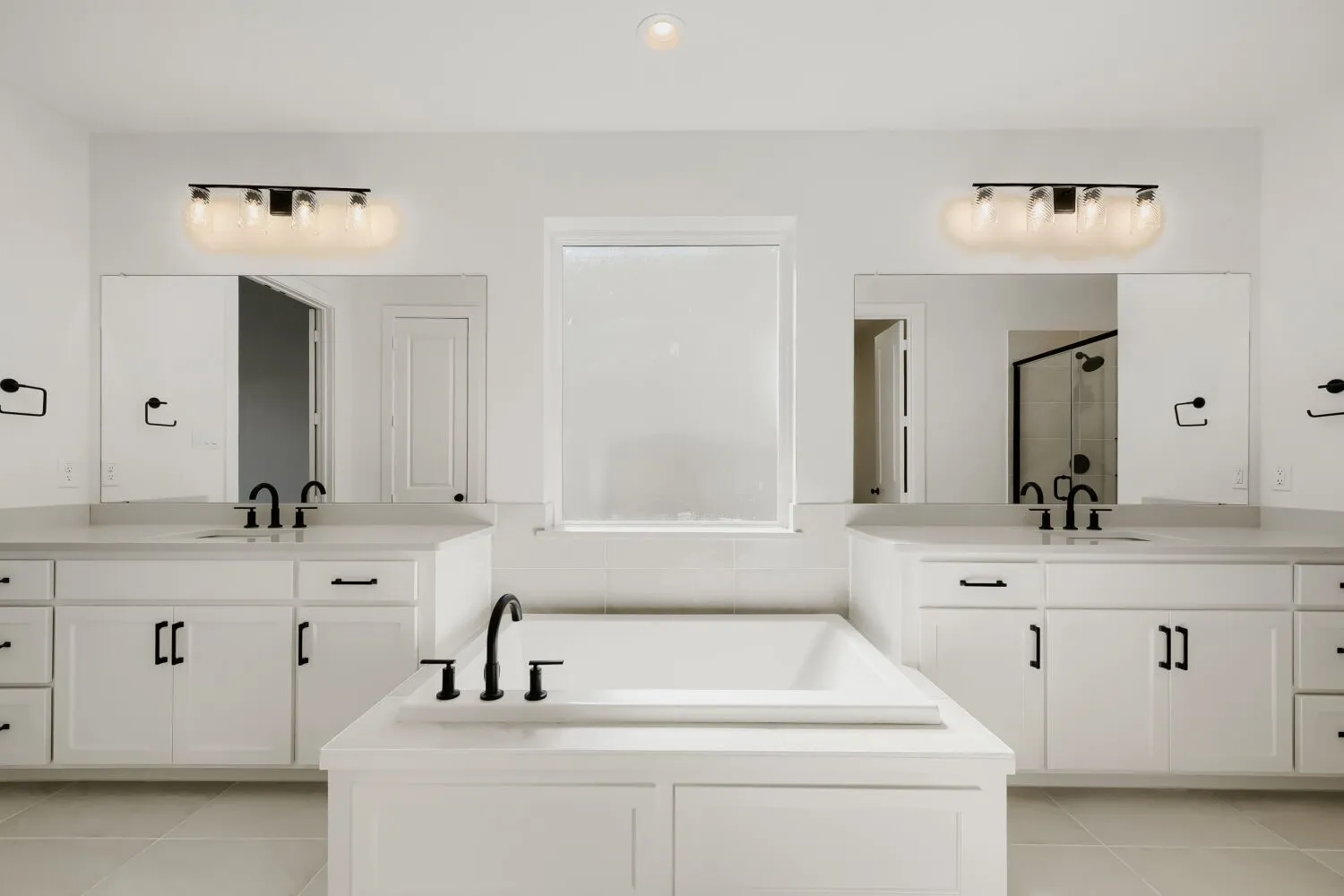 Dual vanities with matte black fixtures, built-in soaking tub, and tile flooring