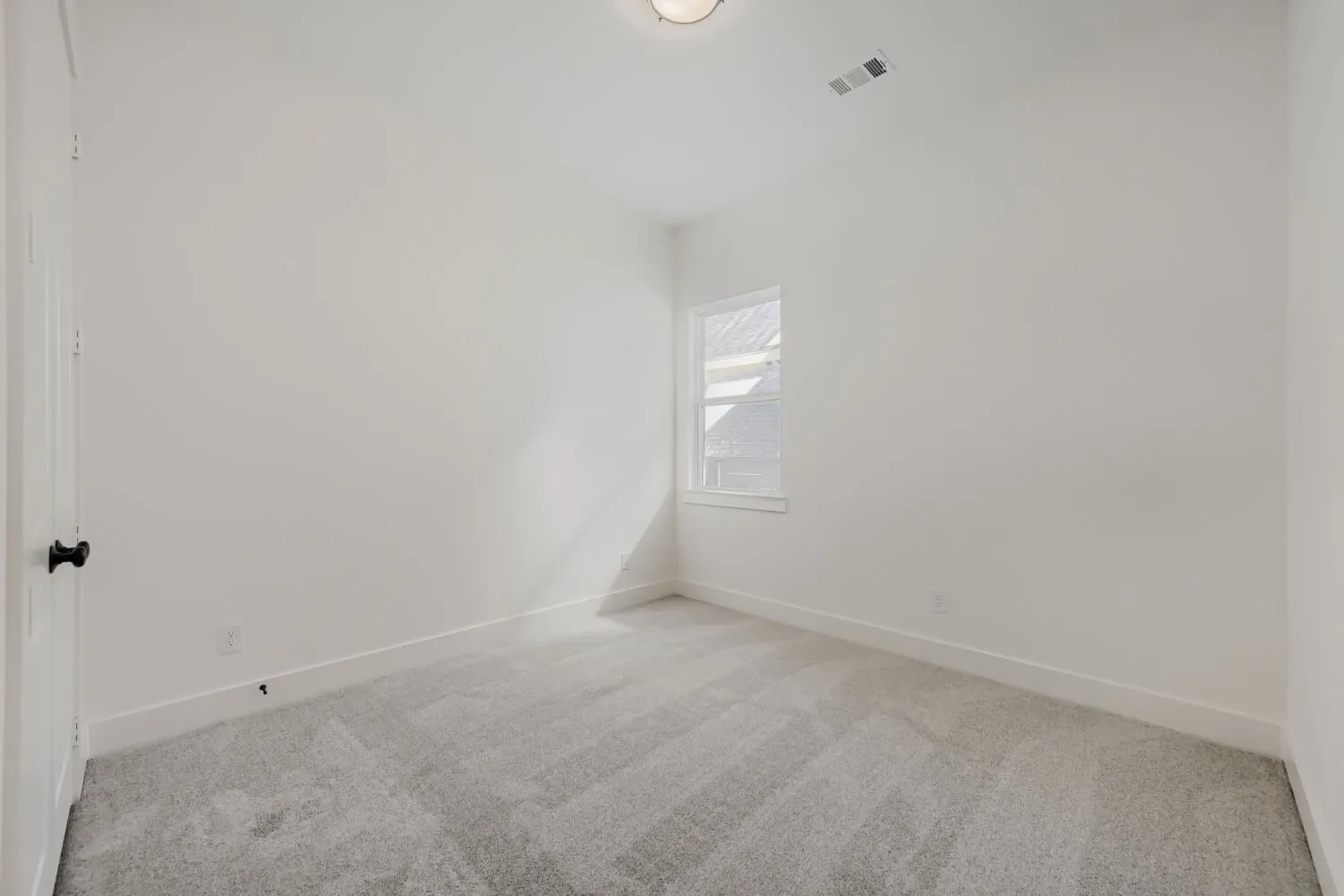 Plush gray carpeting, white walls, and a single window with white trim