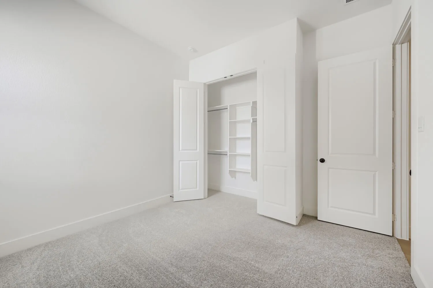 Wall-to-wall carpeting, bright white walls, and built-in closet shelving