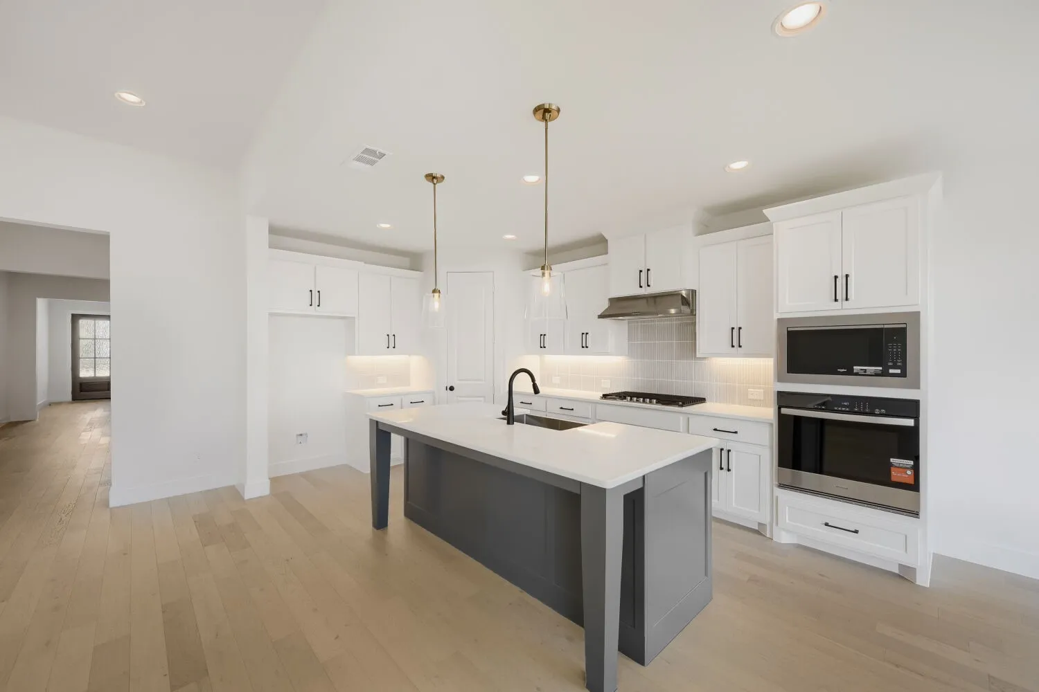 Modern kitchen featuring a dark gray island with a light-colored countertop, white shaker-style cabinetry, and stainless steel appliances