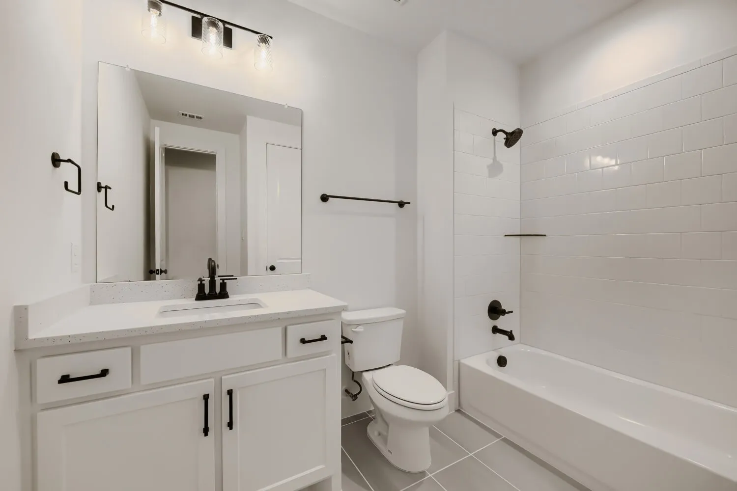 White vanity with black hardware, quartz-finish countertop, and undermount sink