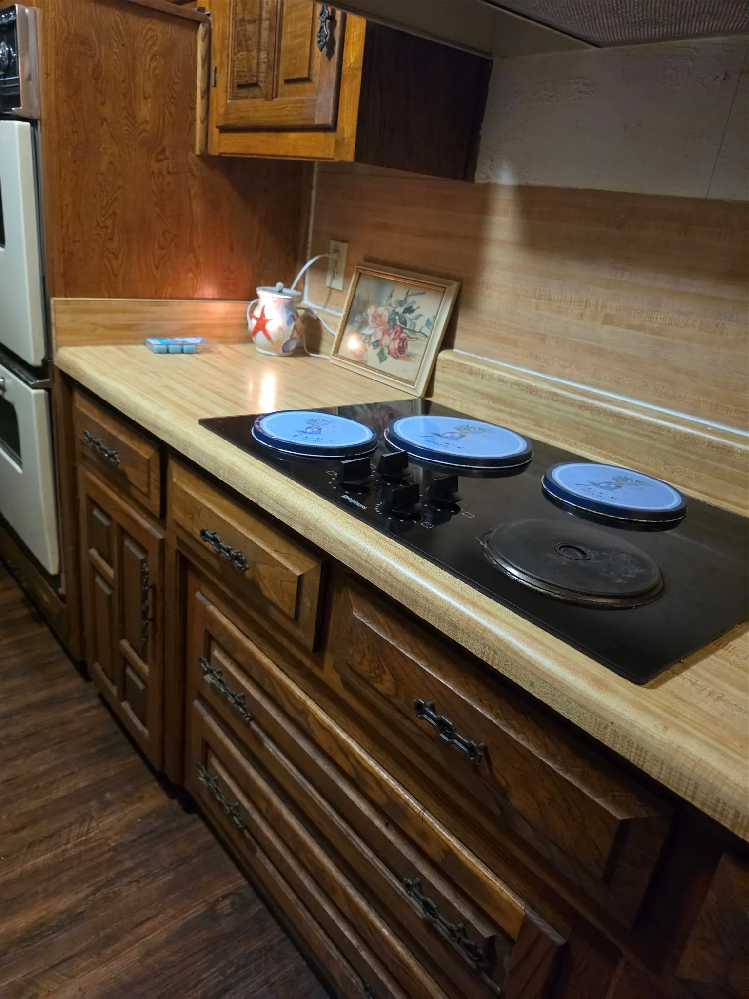 Built-in cooktop, laminate countertop, wood-finish cabinetry, wood-finish flooring, and built-in oven