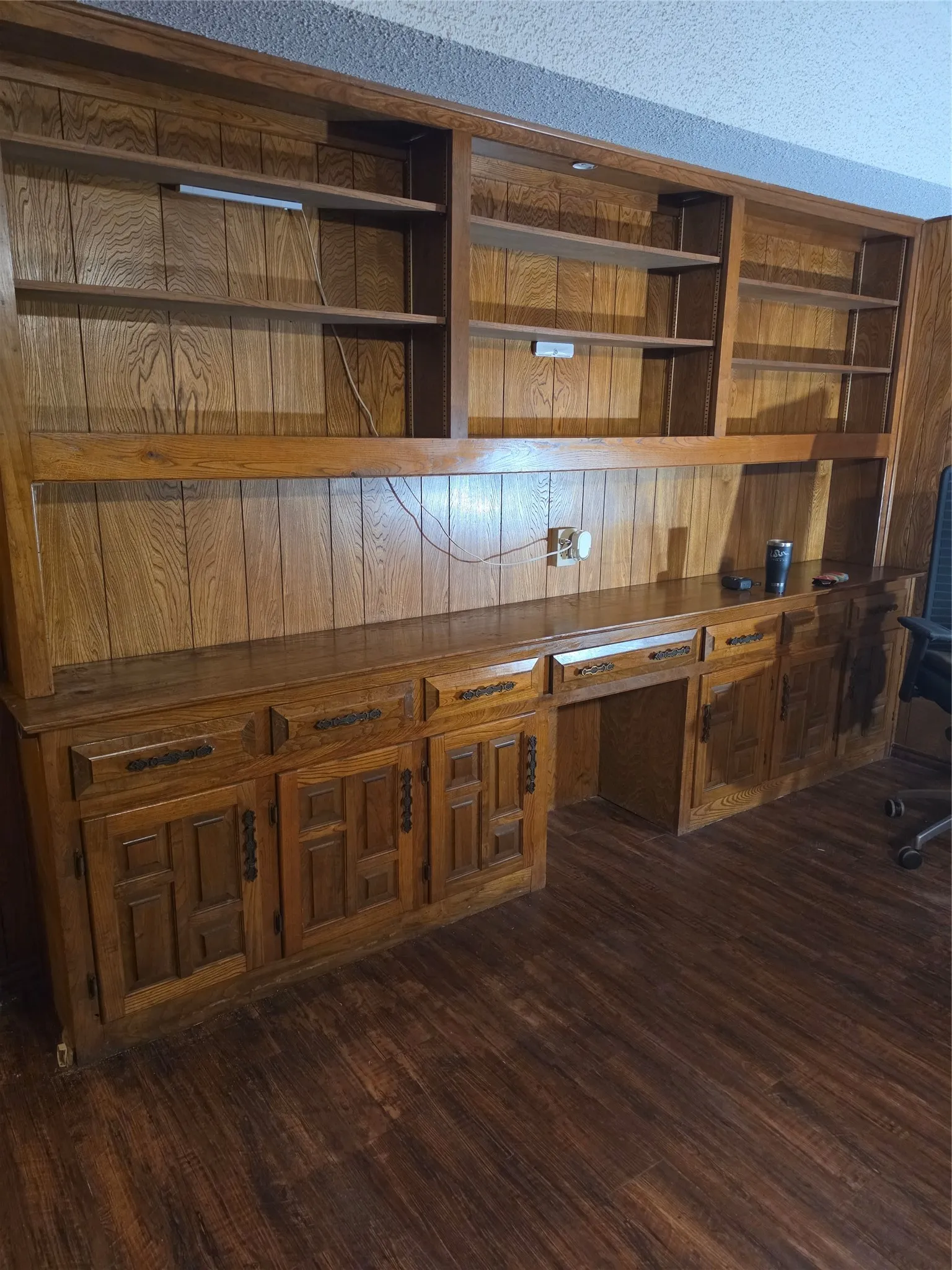 Built-in cabinetry with wood-finish paneling, integrated desk space, and open shelving