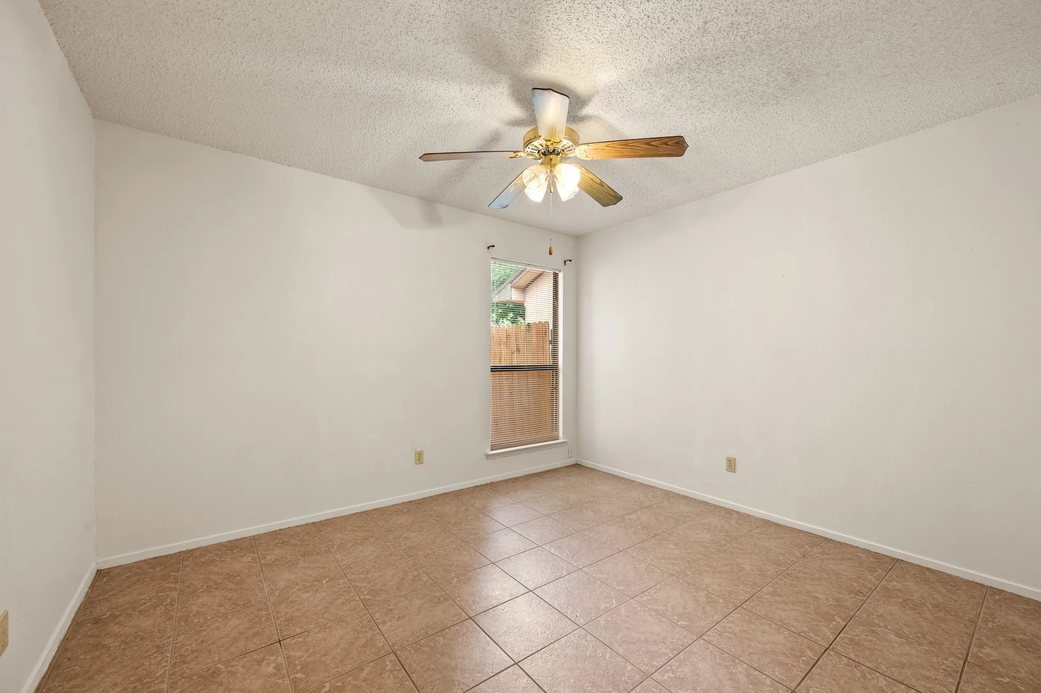 Neutral paint palette with a textured ceiling, tile flooring, and a ceiling fan with light fixture