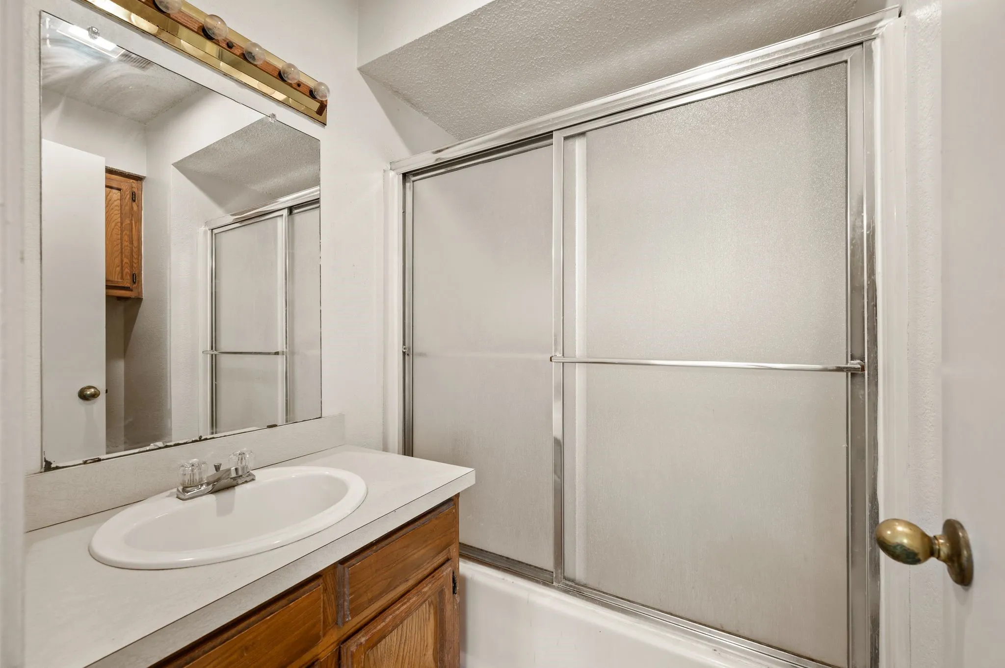 Vanity with an integrated sink, wood-finish cabinetry, and a framed mirror