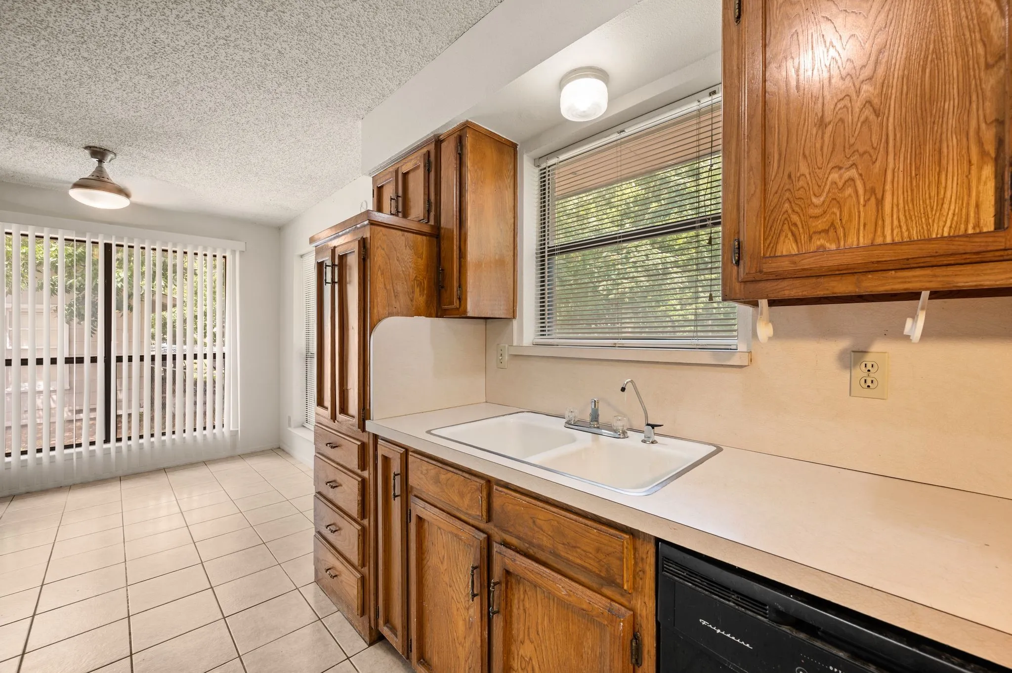 Kitchen featuring wood cabinetry, a double basin sink, and integrated dishwasher