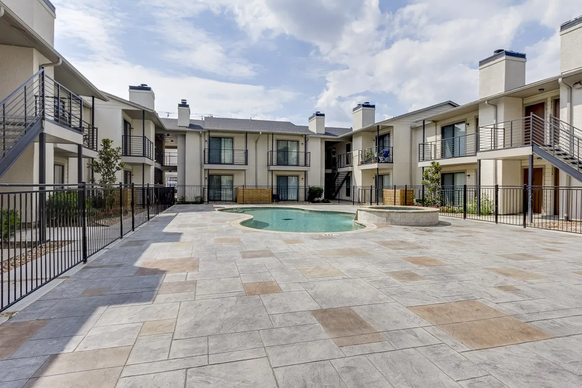 Resort-style courtyard anchored by a sparkling pool, surrounded by multi-unit residential architecture featuring modern facades with stone and metal accents