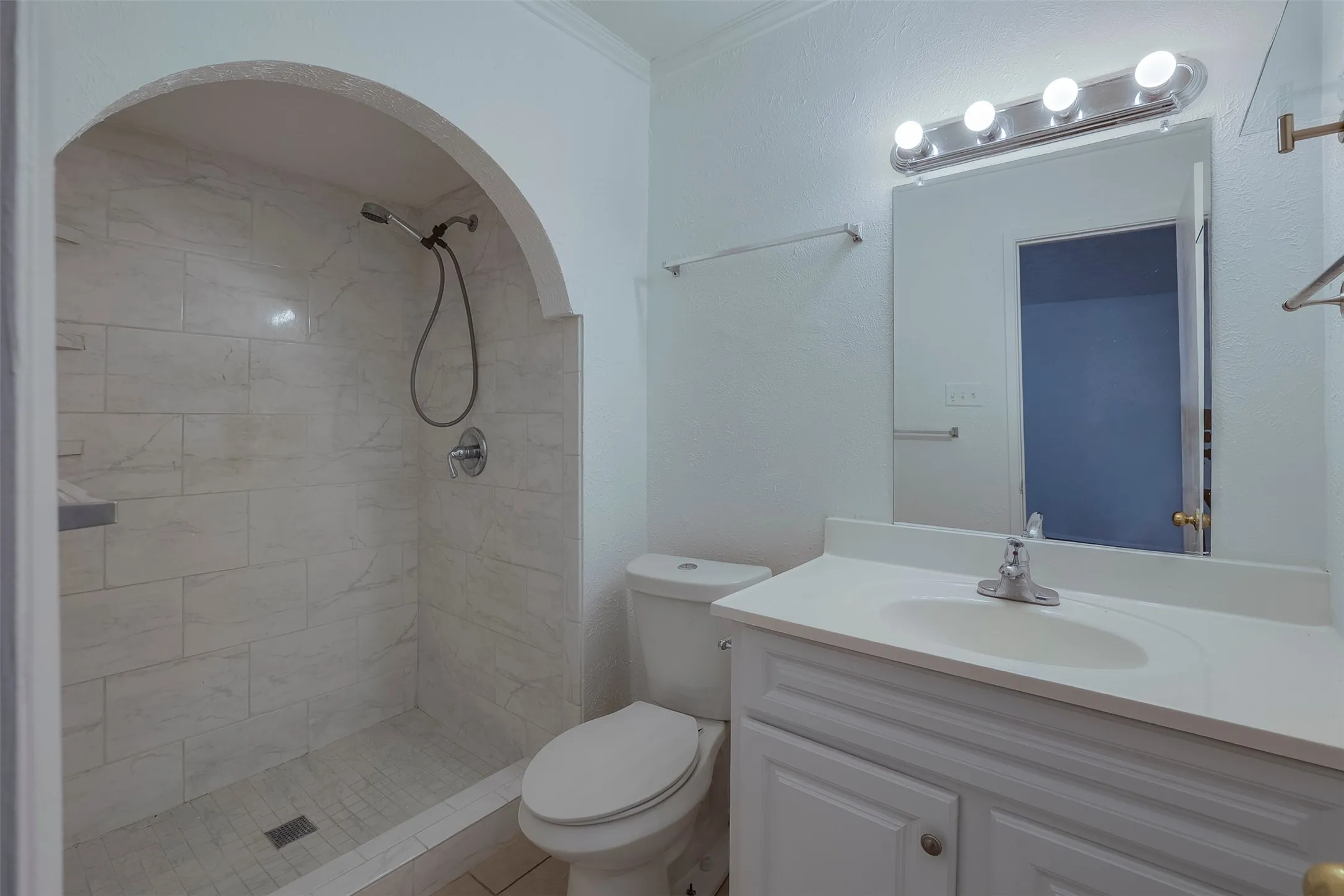 Modern bathroom featuring a spacious walk-in shower with tile surround and curved glass enclosure, white vanity with ample counter space, vessel sink, contemporary chrome fixtures, and illuminated mirror with integrated lighting