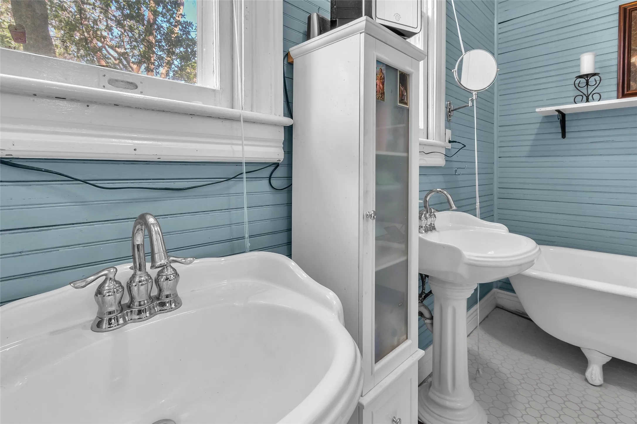 Bright bathroom with a double sink, porcelain fixtures, shiplap walls, and large windows allowing ample natural light.