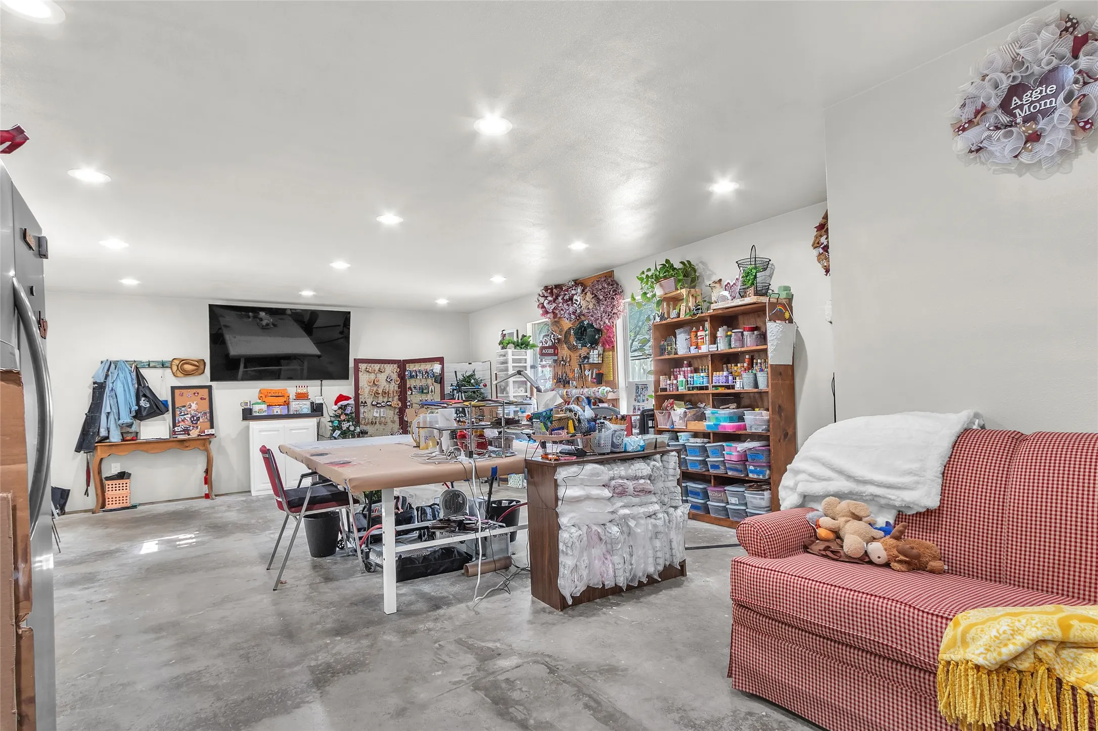 Workshop space with concrete floors, recessed lighting, multiple shelves for storage, and a layout suitable for crafting or potential ADU conversion