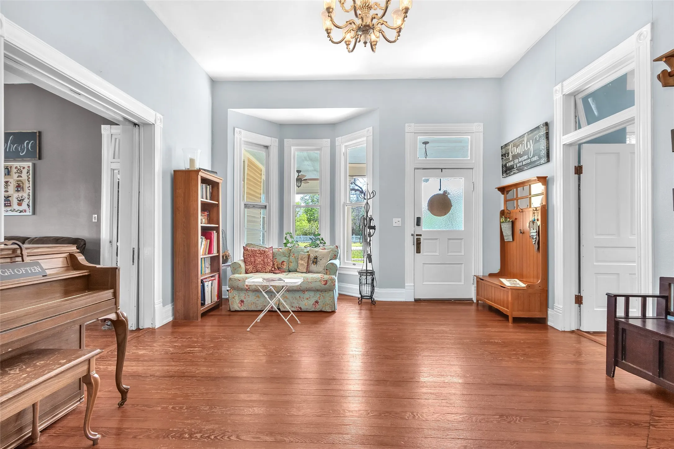 Entryway with hardwood flooring, large windows for natural light, and a welcoming layout showcasing a cozy seating area and accent furniture.