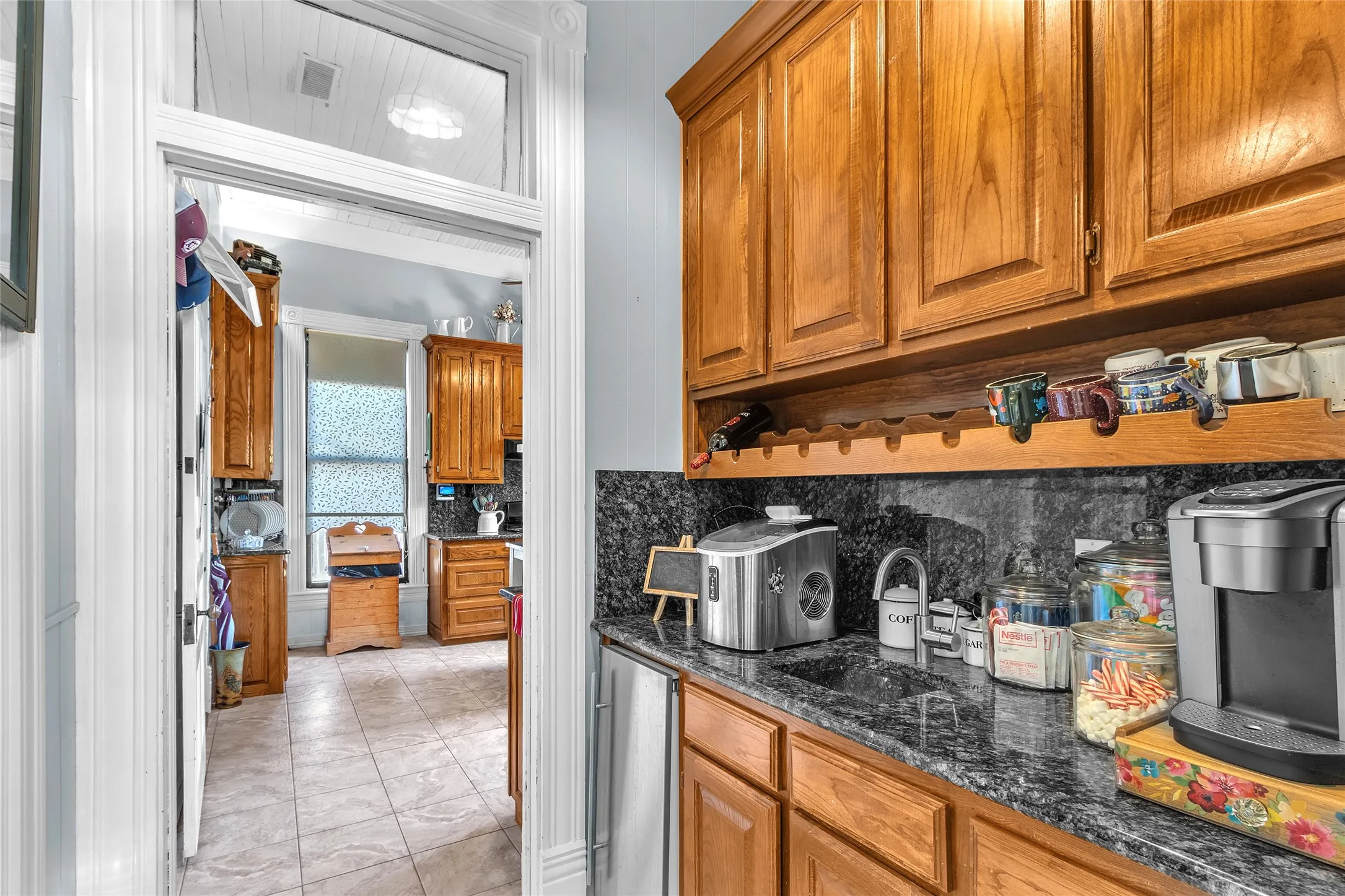Kitchen with wood cabinetry, granite countertops, and stainless steel appliances, illuminated by natural light from adjacent windows.