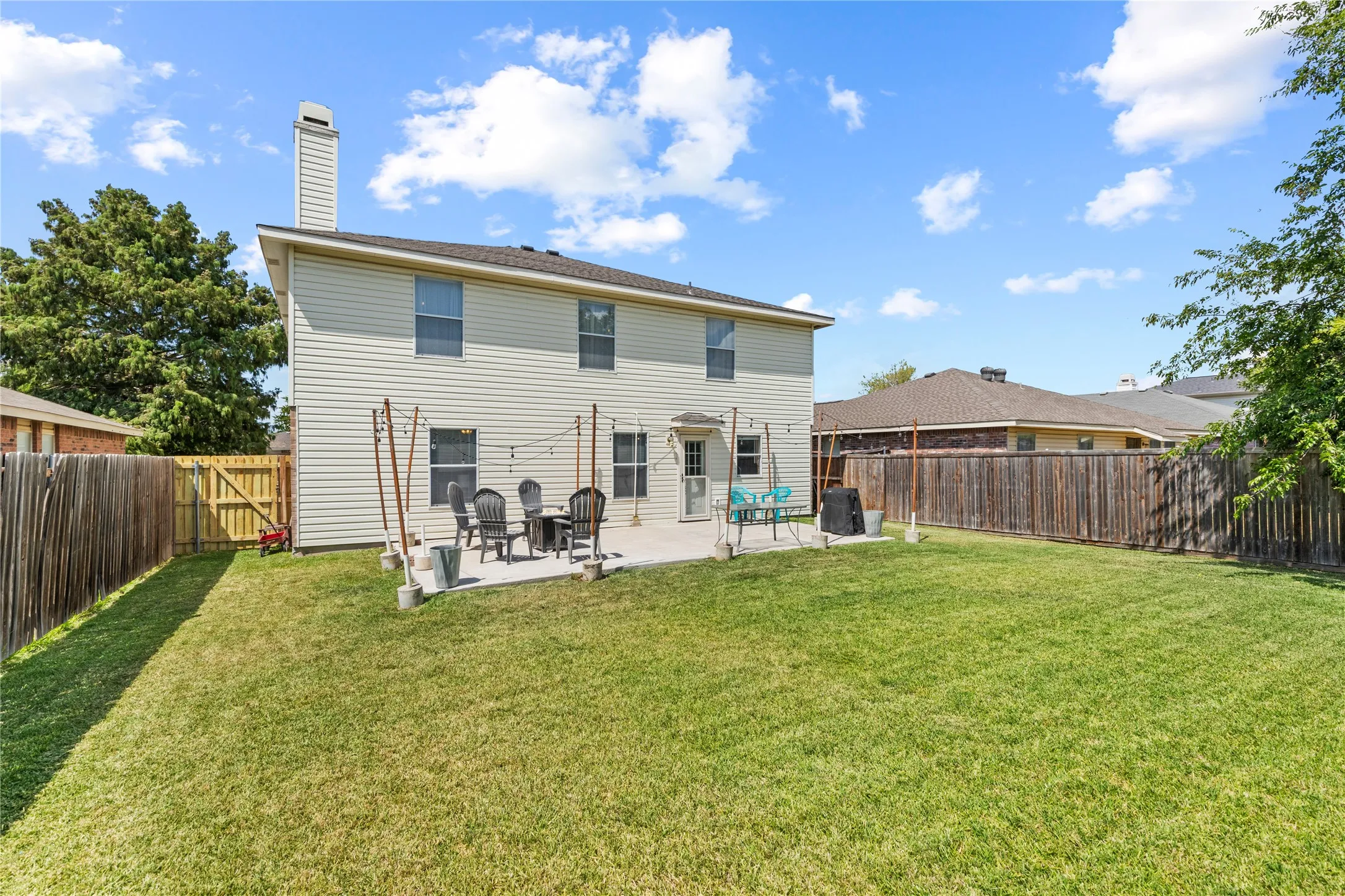 Expansive backyard with a manicured lawn, full privacy fencing, and a concrete patio