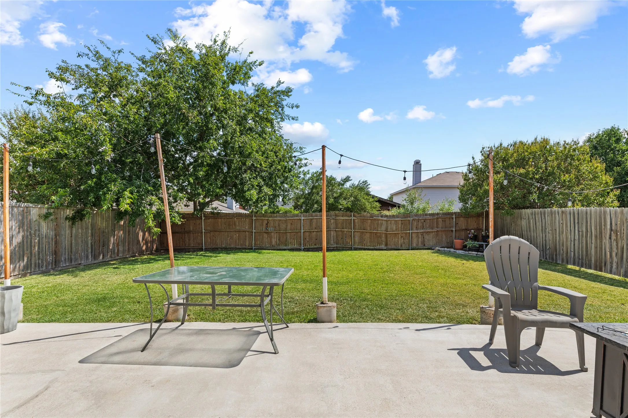 Expansive backyard featuring a concrete patio, a manicured lawn, and a wood privacy fence