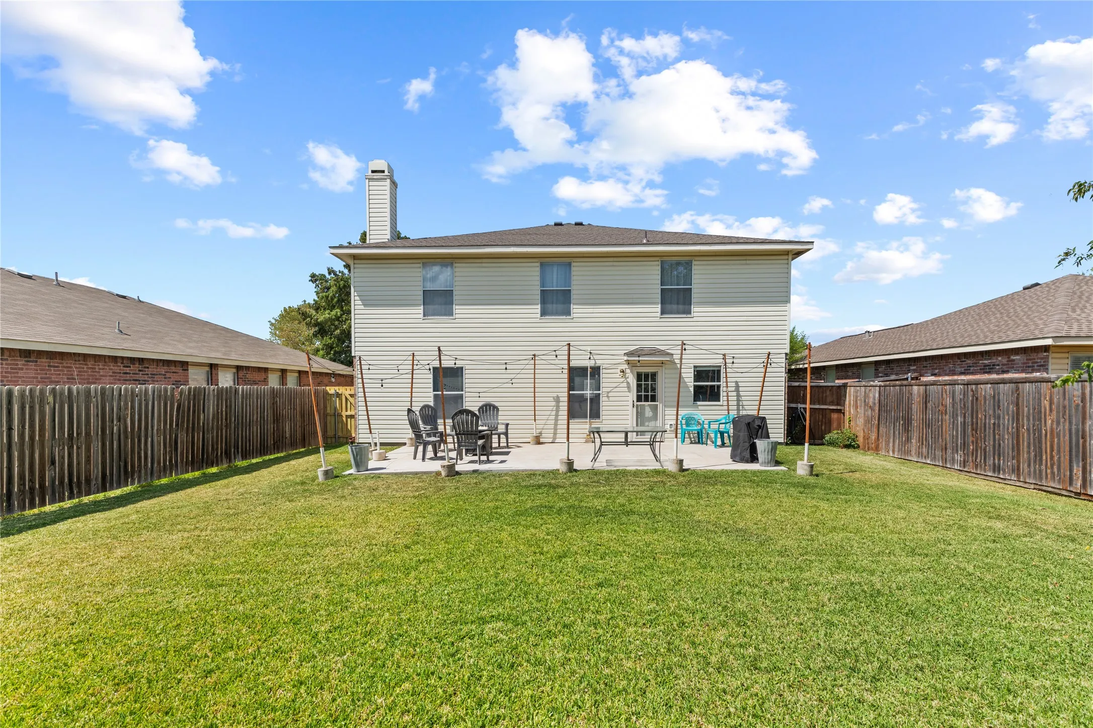 Expansive backyard with a manicured lawn, full privacy fencing, and a concrete patio