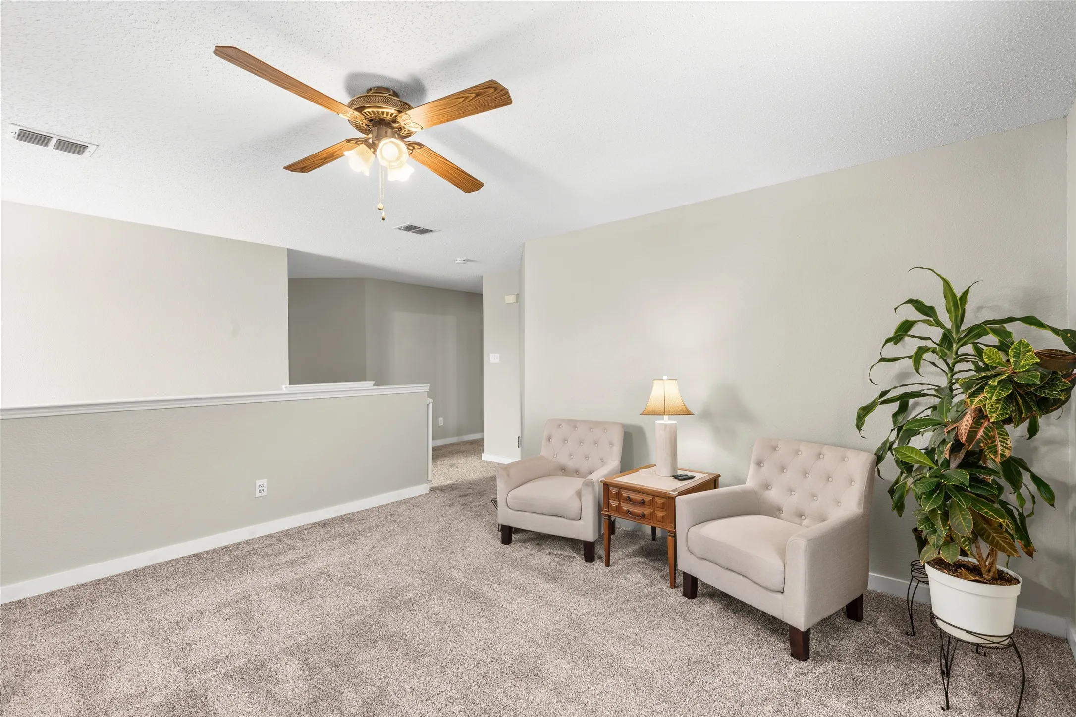 Recessed ceiling fan with light fixture, neutral carpet flooring, and a half-wall partition