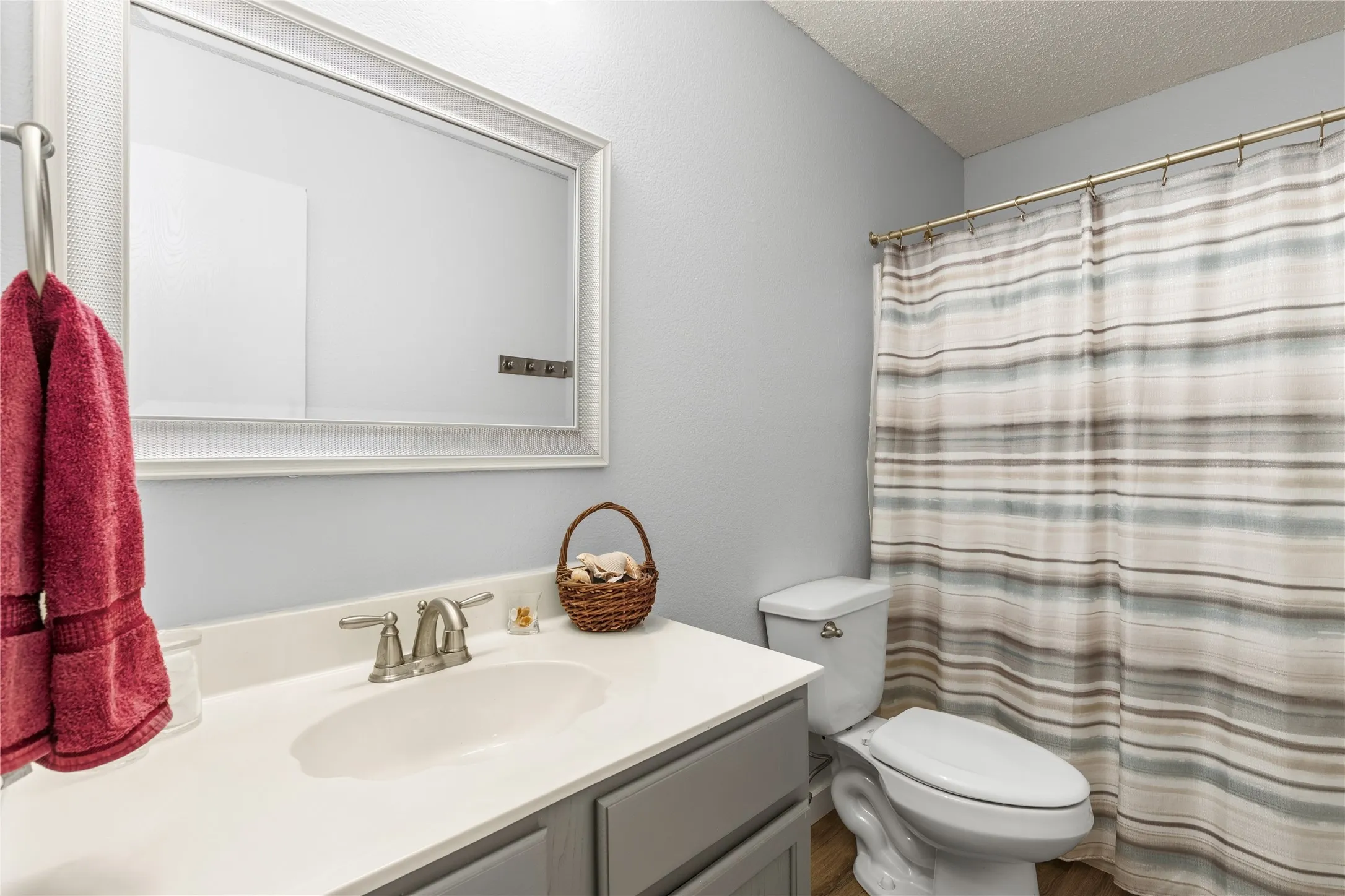 Bathroom featuring a vanity with an integrated sink, brushed nickel faucet, framed mirror, and a toilet