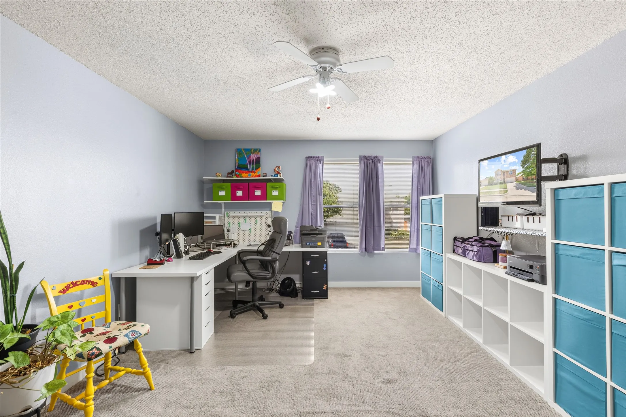 Spacious room with light-colored walls, ceiling fan, and multiple windows providing natural light
