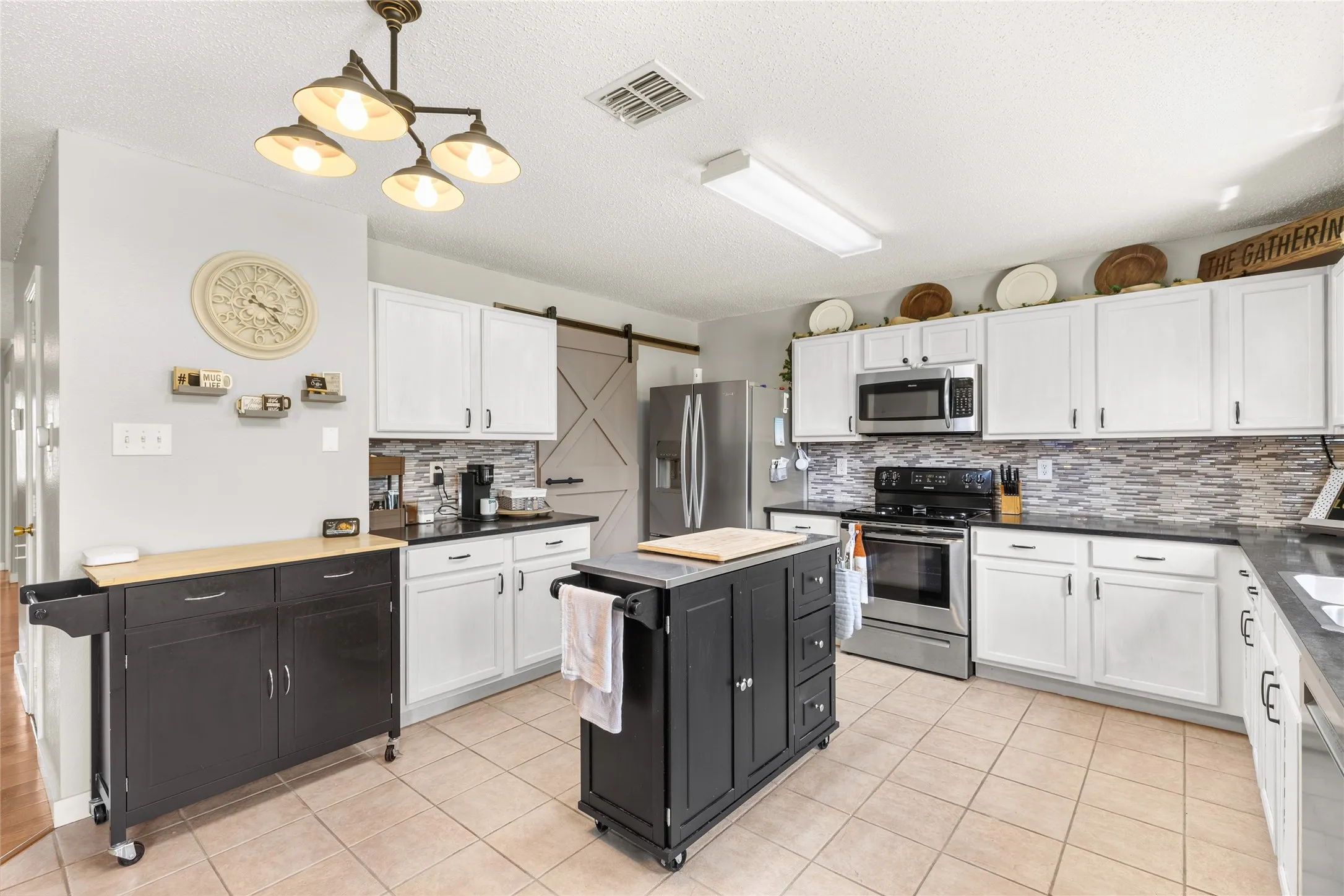 Kitchen featuring white cabinetry, dark countertops, a mosaic tile backsplash, stainless steel appliances, and tile flooring