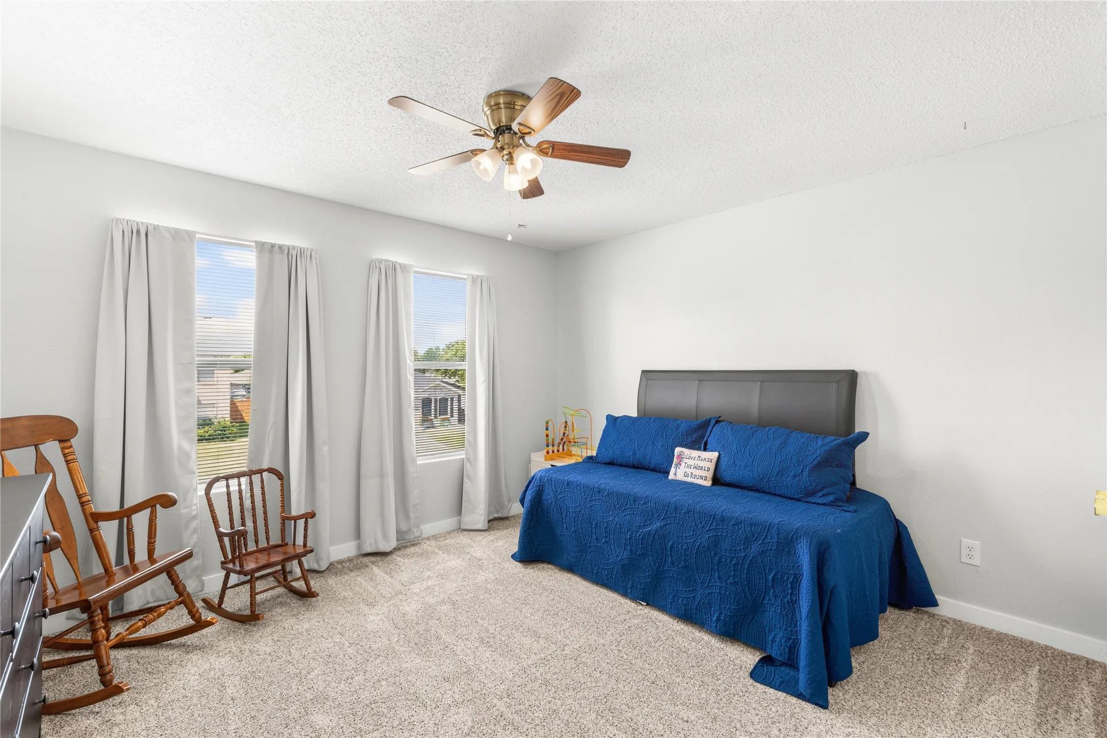 Carpeted flooring, two windows, and a ceiling fan with integrated lighting