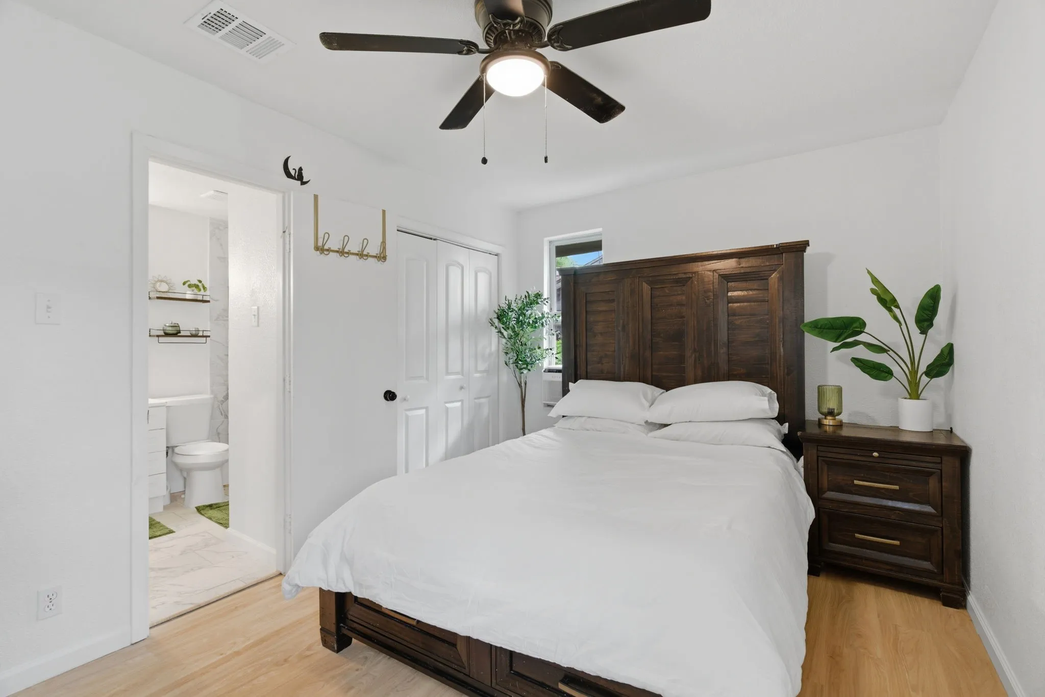Bedroom featuring light wood finished floors, a closet, a ceiling fan, and connected bathroom