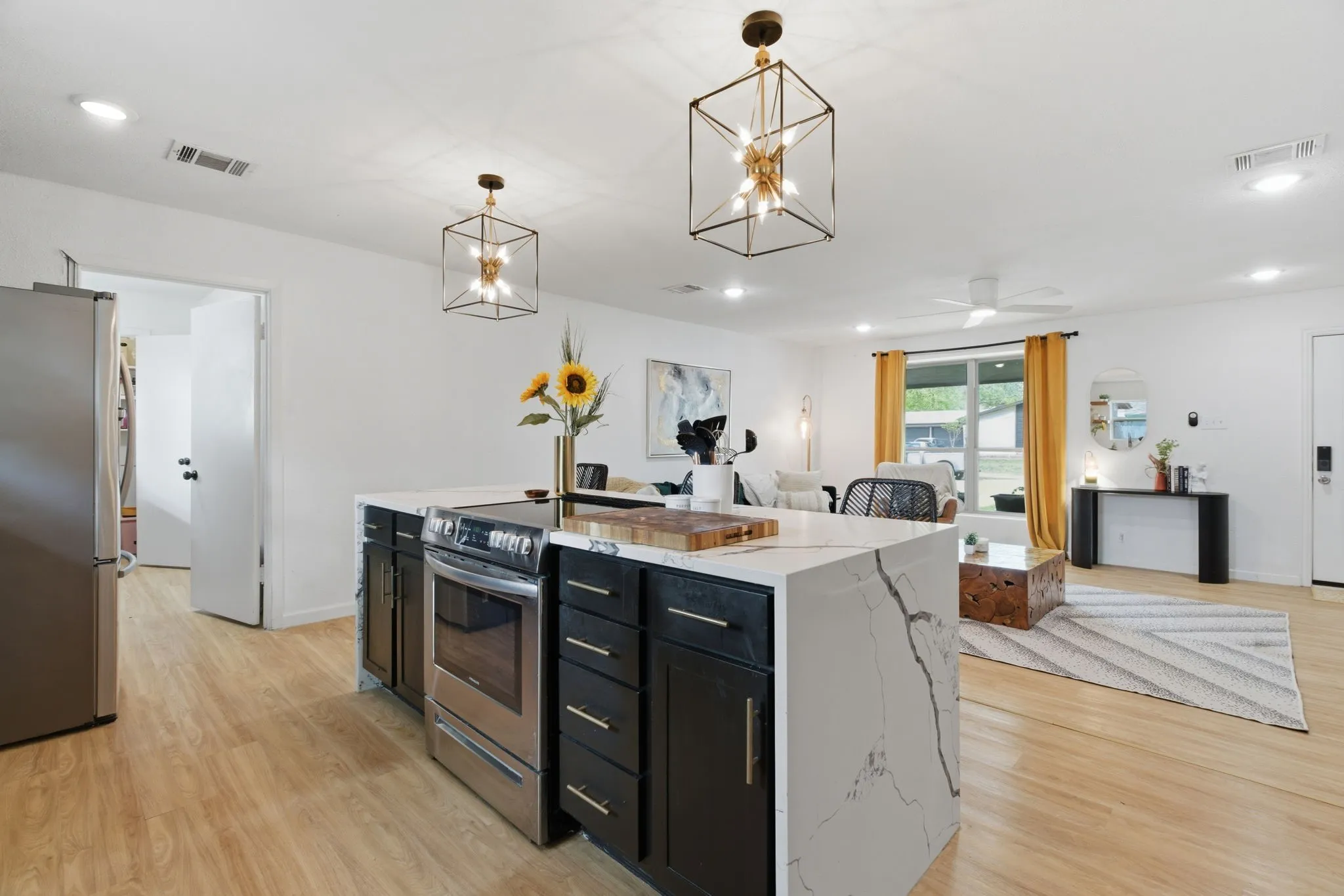 Kitchen featuring dark cabinetry, open floor plan, stainless steel appliances, a kitchen island, and light wood-type flooring