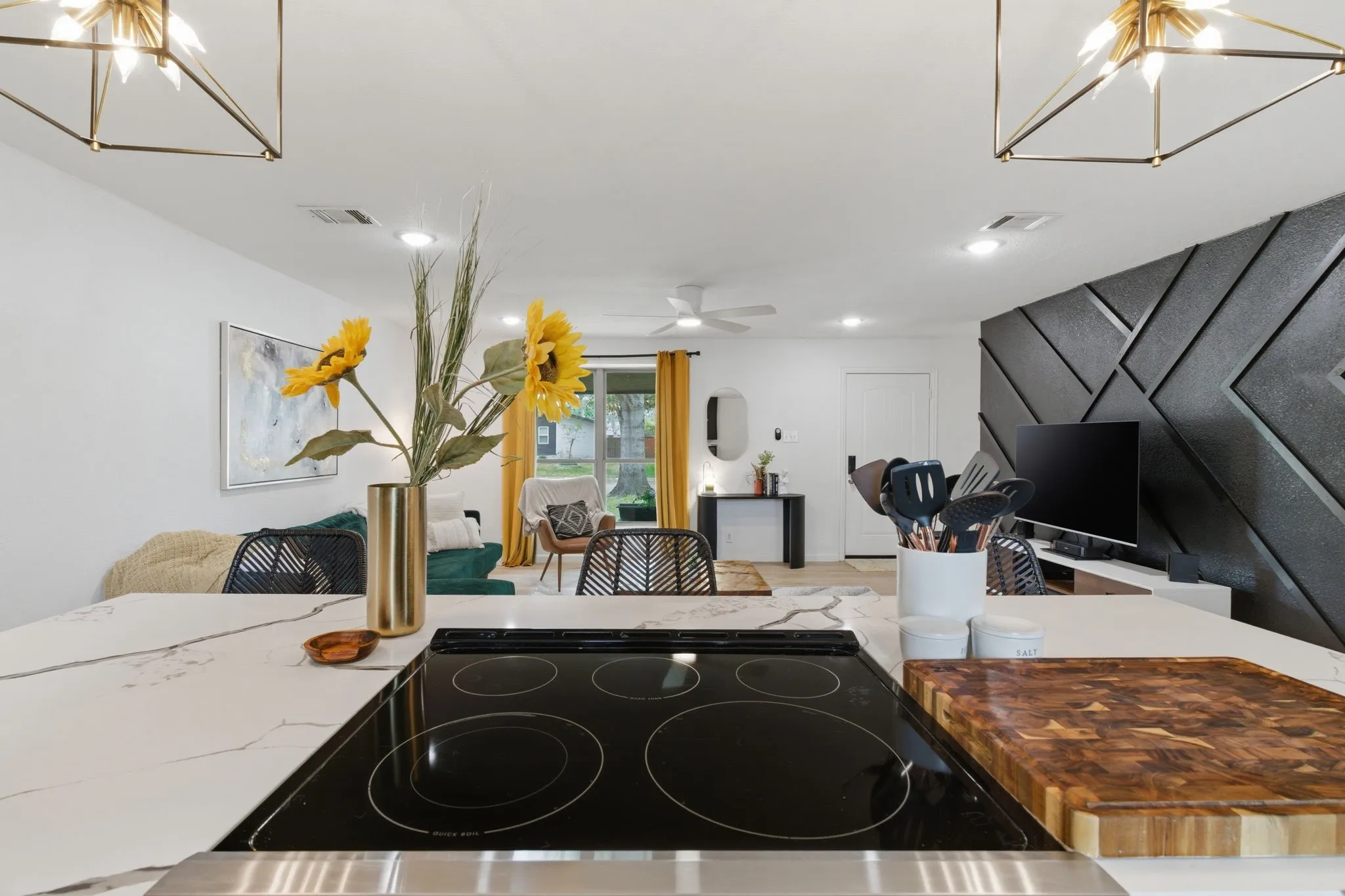 Kitchen with hanging lights, black electric stovetop, open floor plan, and ceiling fan