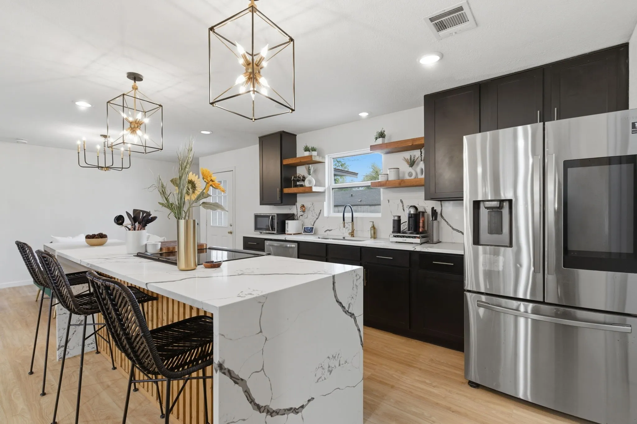Kitchen with a breakfast bar area, stainless steel appliances, open shelves, a kitchen island, and light wood-style flooring