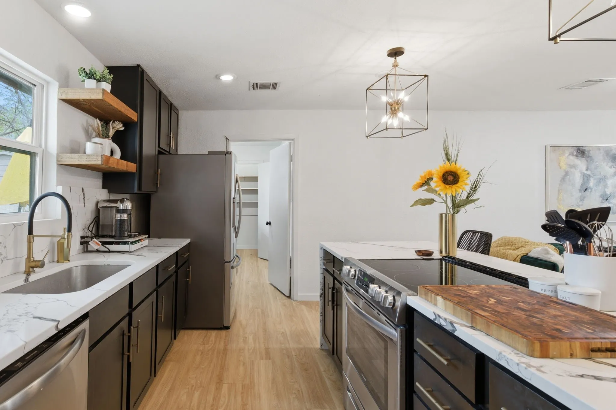 Kitchen with stainless steel appliances, light wood-style floors, light stone countertops, and open shelves