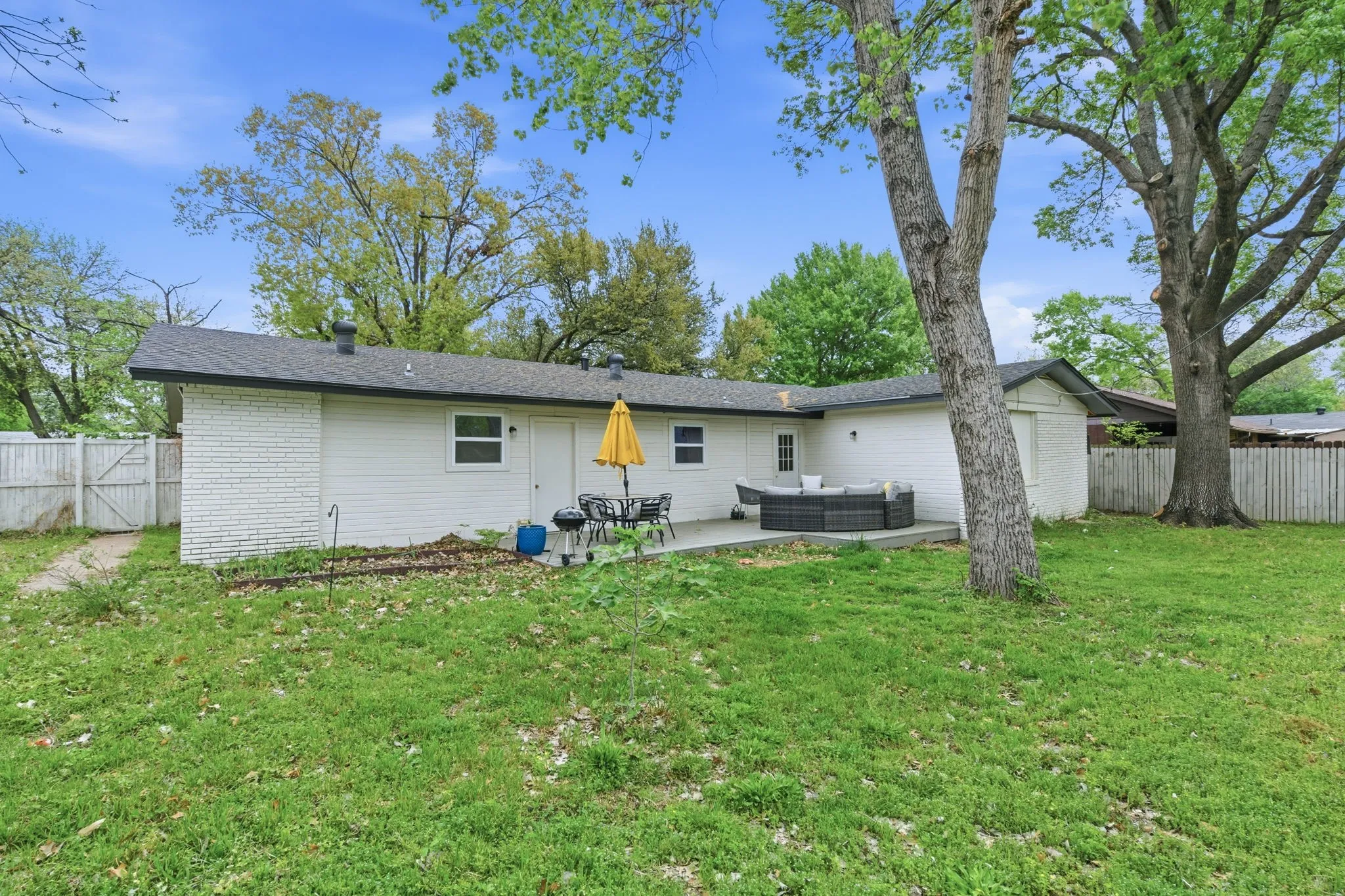 Rear view of property with outdoor seating, a patio area, a fenced backyard, brick siding, and a gate