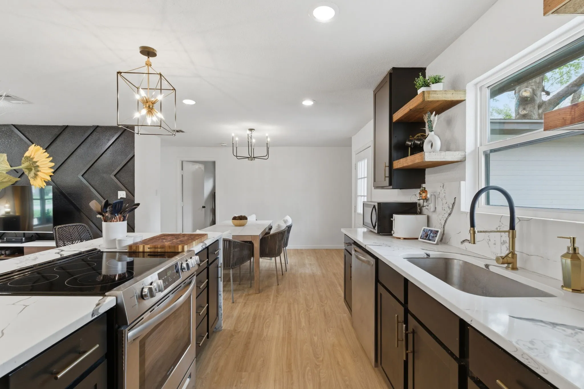 Kitchen with stainless steel appliances, light stone counters, open shelves, light wood finished floors, and dark wood finish cabinetry