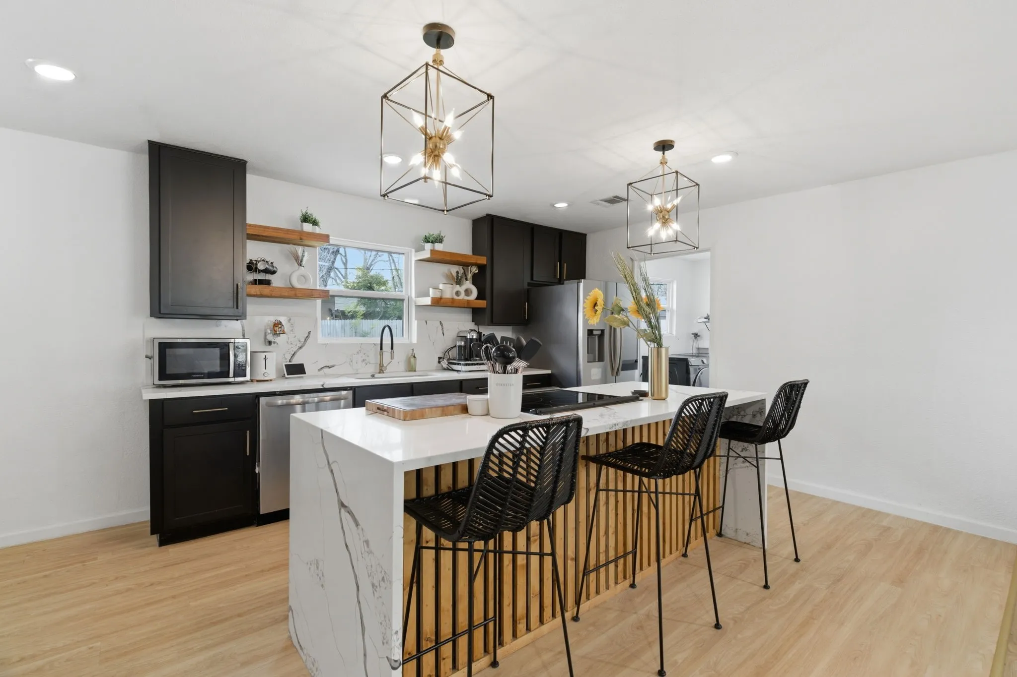 Kitchen featuring a breakfast bar, open shelves, a kitchen island, dark cabinets, and light wood finished floors