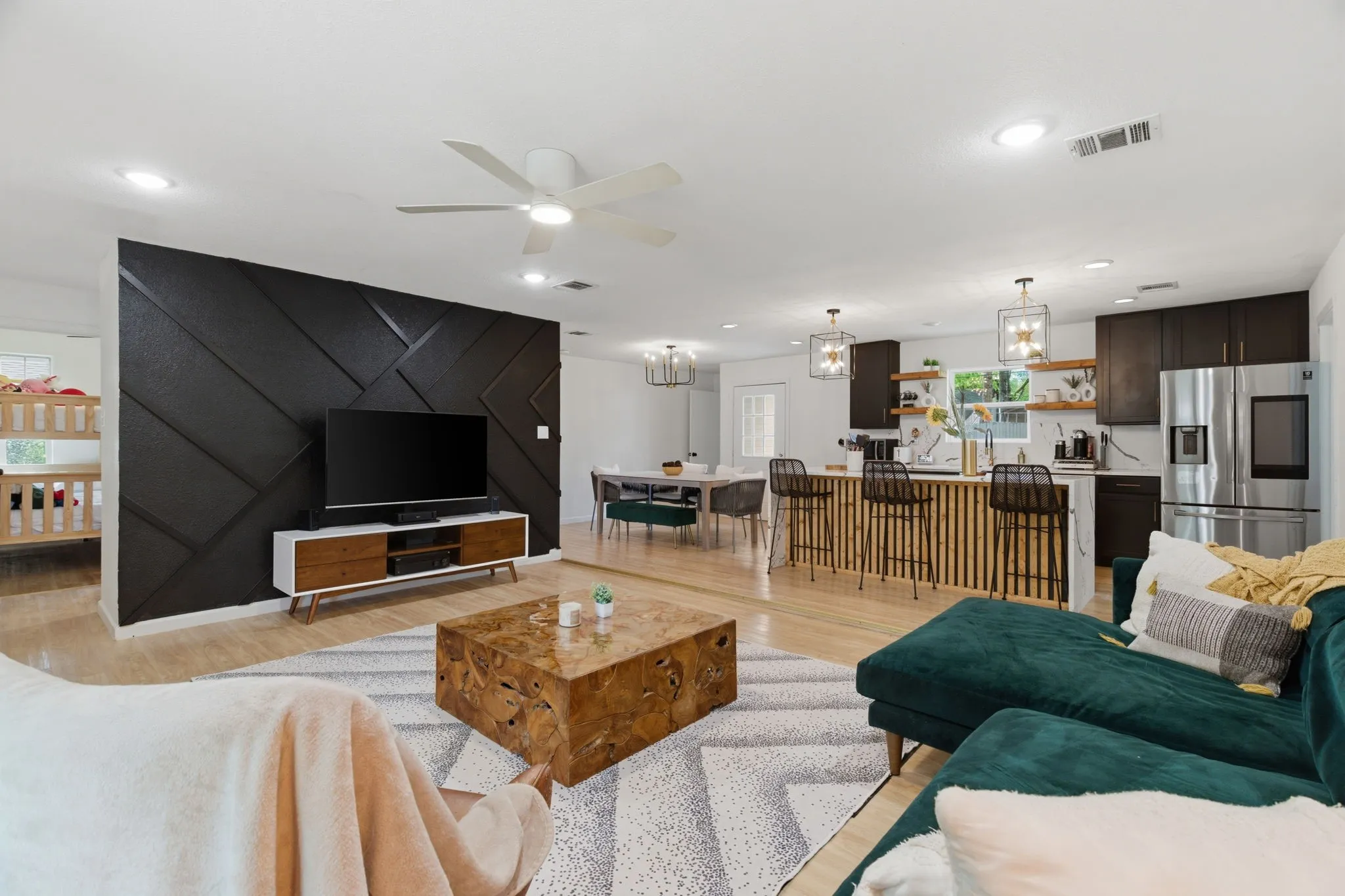 Living room featuring light wood-type flooring, ceiling fan, and hanging lights